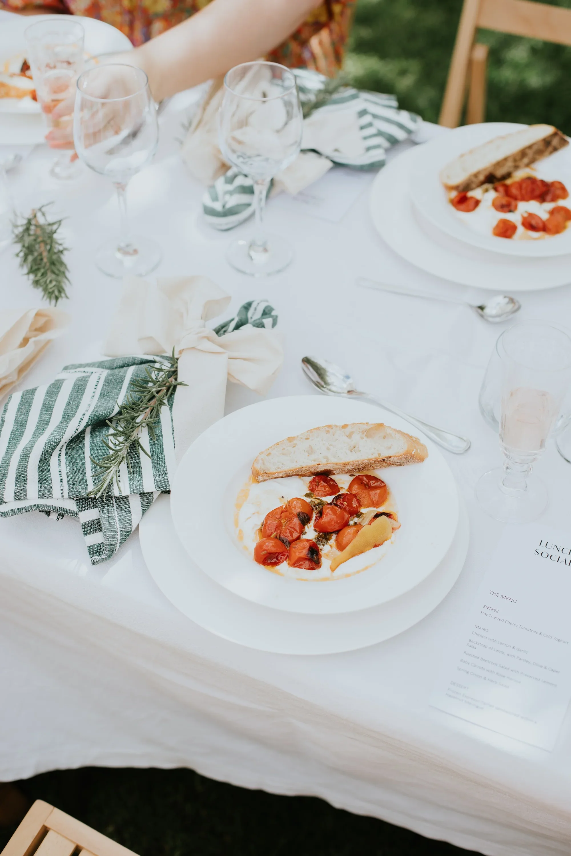 A roast tomato starter on a beautifully scaped table.