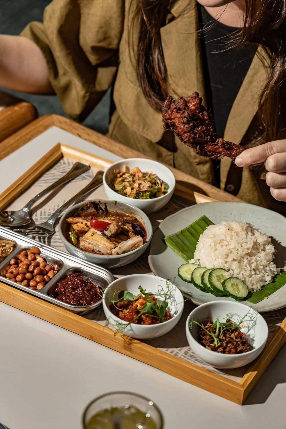 A diner sharing fried chicken, coconut rice, sambal, and sides at The Coconut Club Beach Road