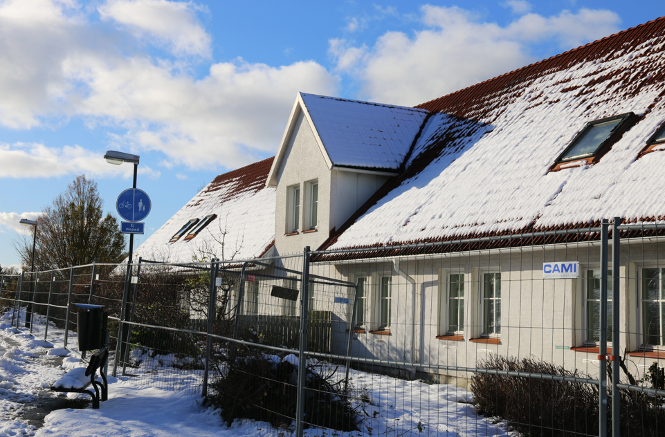 Vit byggnad bakom ett byggstängsel vid byggarbetsplatsen för projektet Lastvagnen.