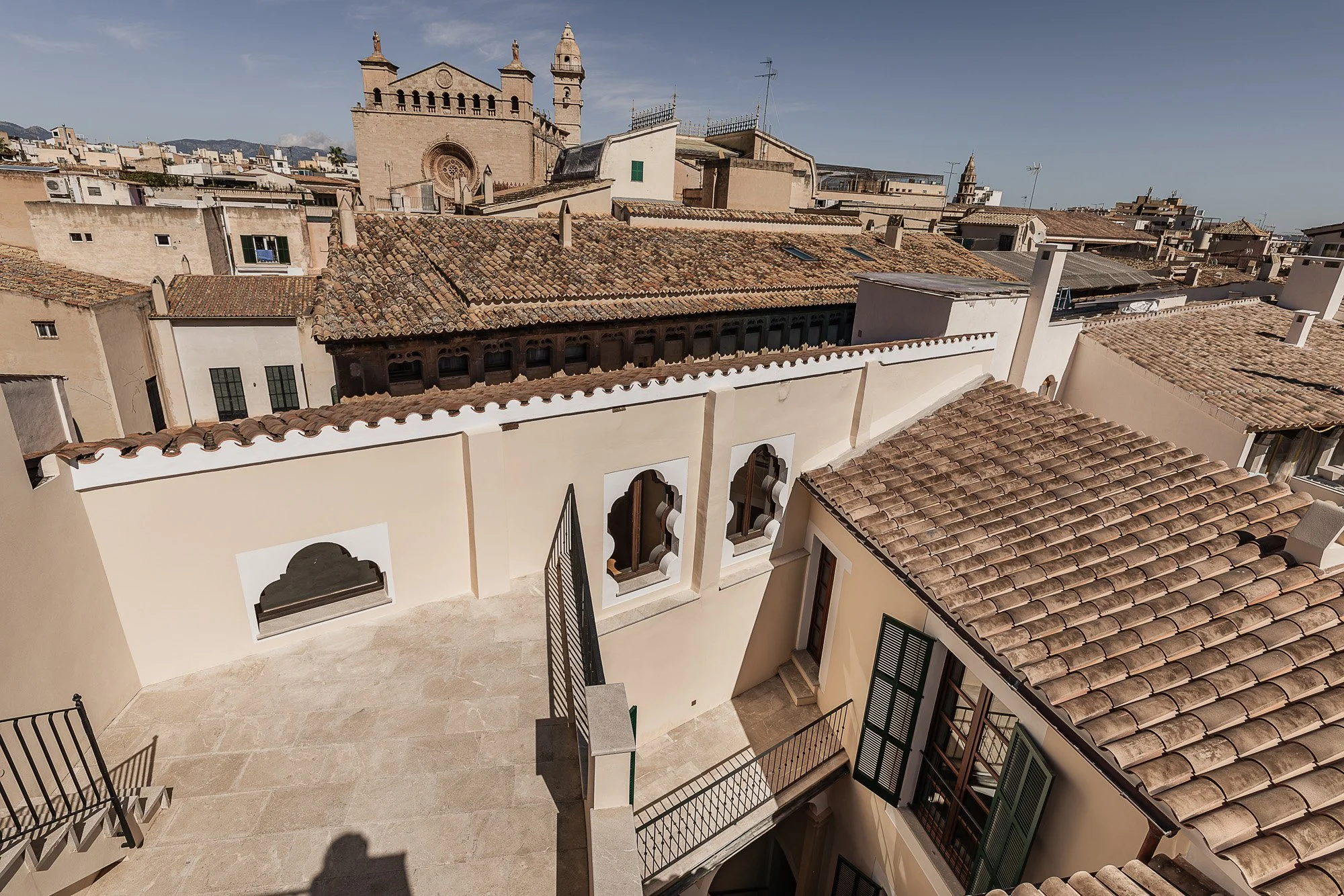 View of historic European city rooftops with terracotta tiles, church, and cityscape.