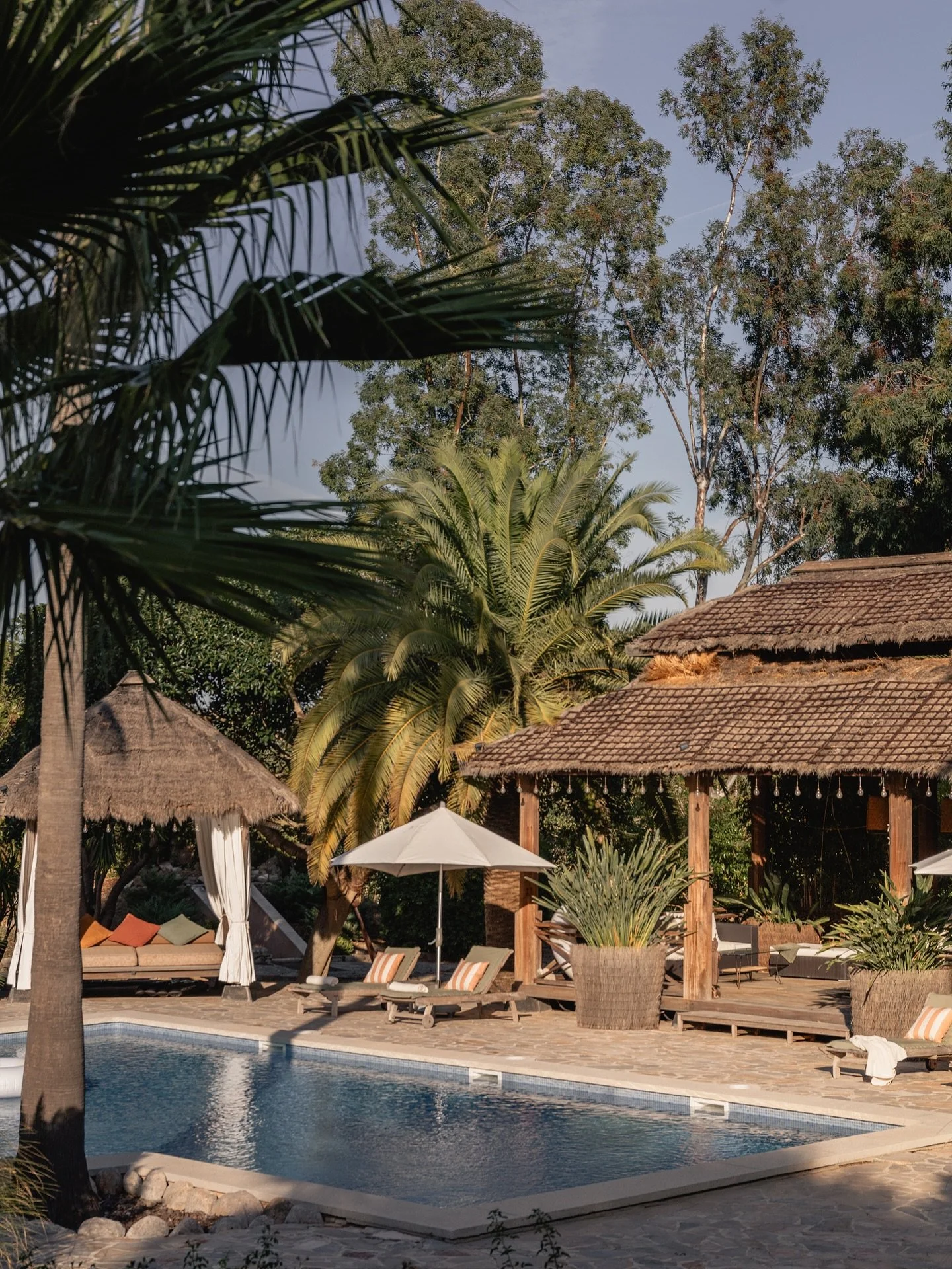 It feels almost unreal &mdash; this quiet corner of Mallorca that looks and breathes like a private resort.
Palms sway above the water, the air smells faintly of sun and wood, and the mountains stand behind it all &mdash; steady, golden, timeless.

T