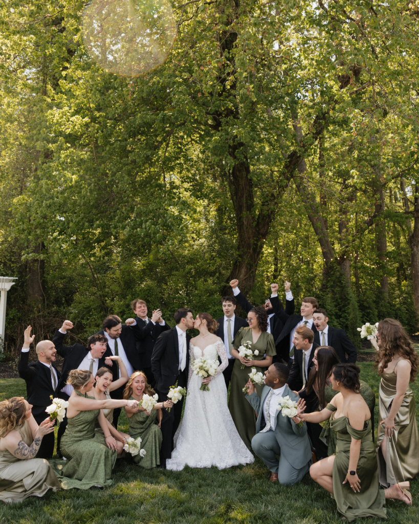 A bride and groom standing together outside a modern white wedding reception pavilion surrounded by trees and garden decor.