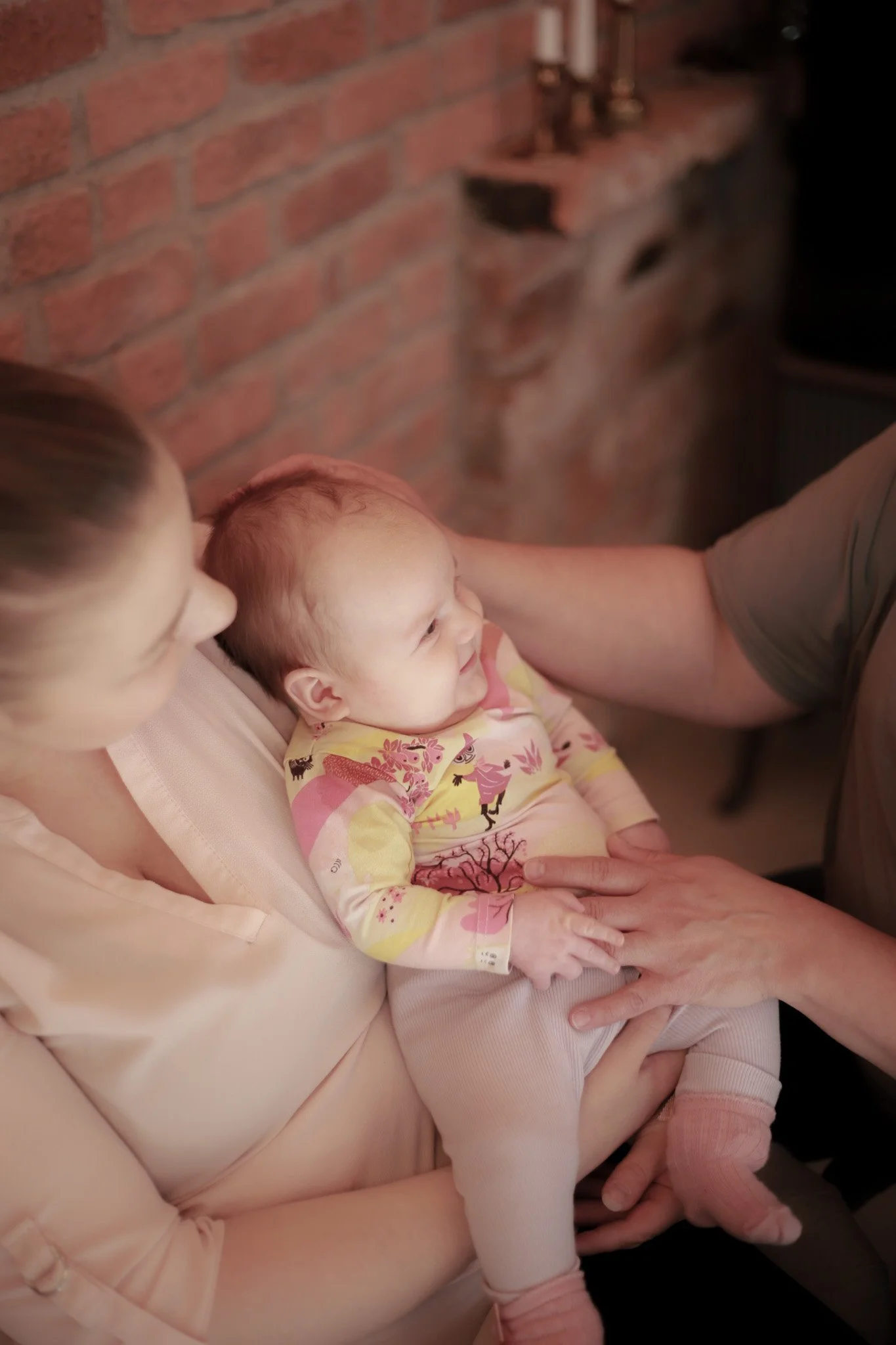 Äidillä on kahden kuukauden ikäinen vauva sylissä ja hoitaja koskettaa vauvaa äidin sylissä.