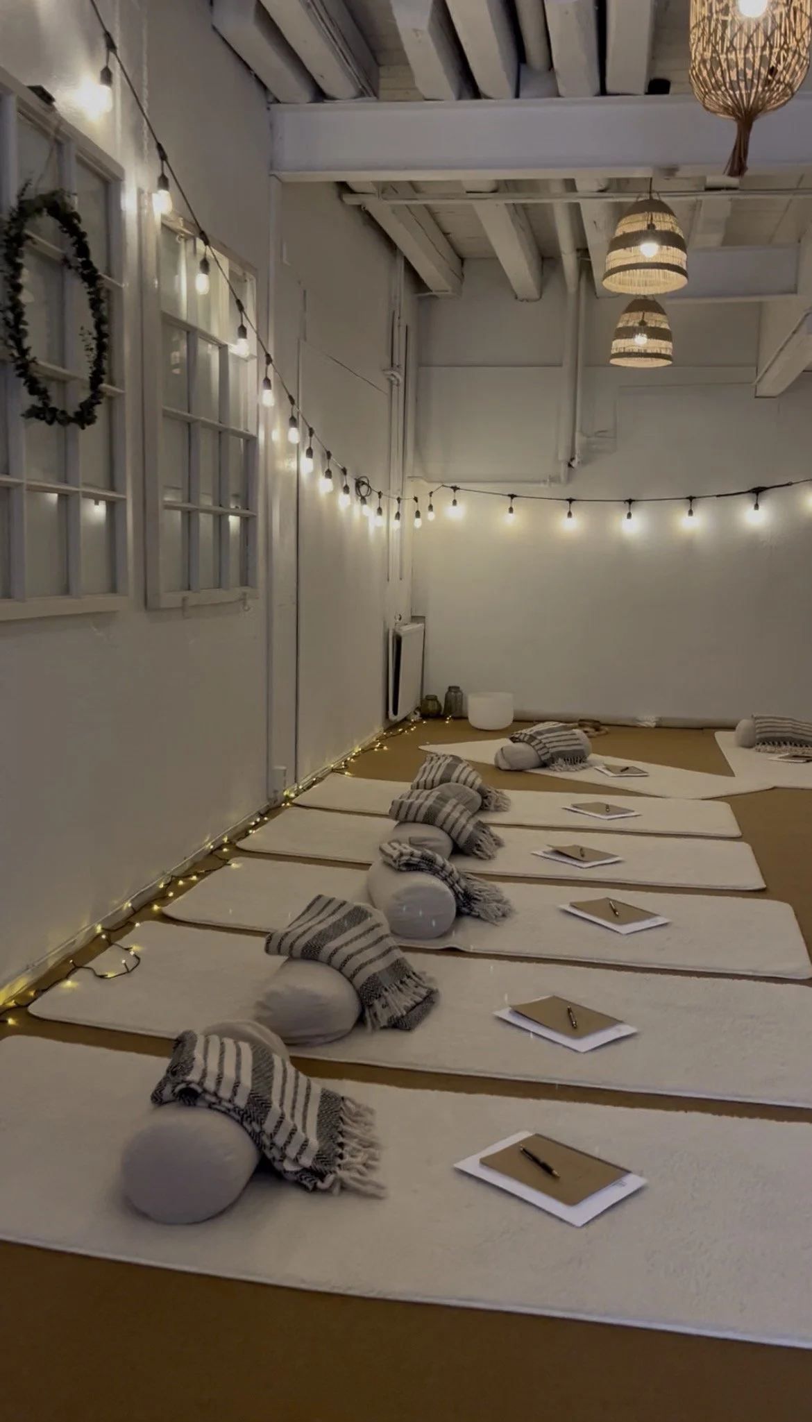 Hiljainen joogatilaisuus sisällä ystävällisessä ja kodikkaassa ympäristössä, matoilla ja kirjat esineinä, pehmeä valaistus ja joulukoristeet.