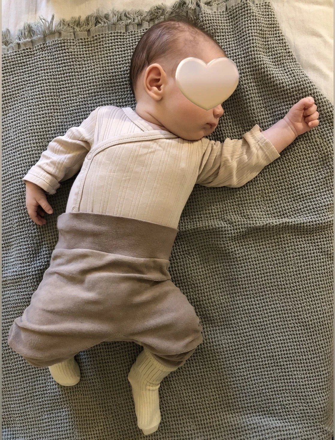 Kolmen kuukauden ikäinen poikavauva nukkuu levollisesti hoitopöydällä, hänen kasvojen edessä on sydän emoji.