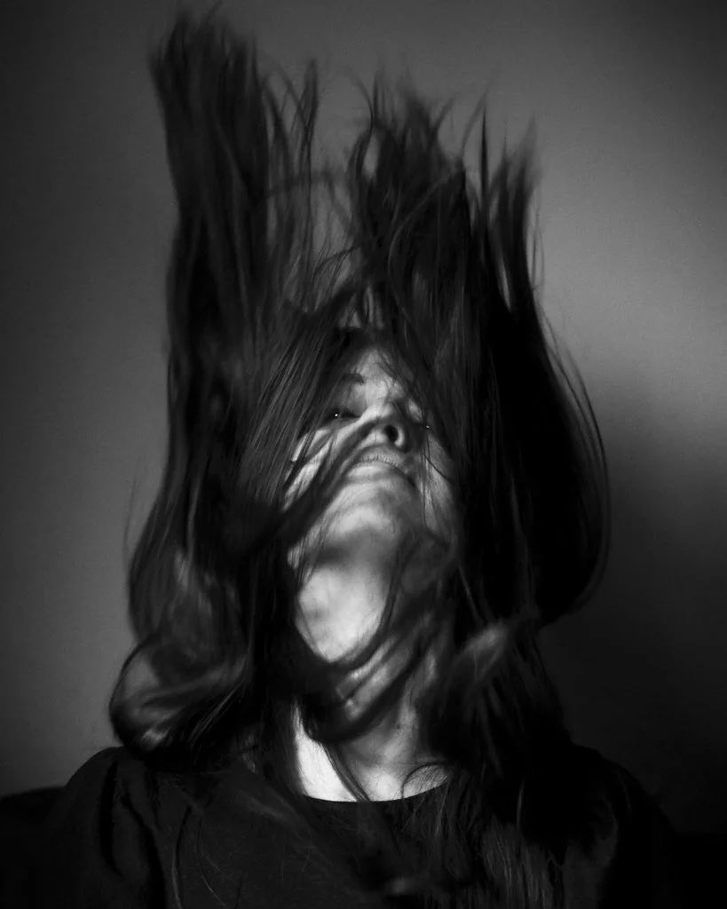 Elizabeth Hansen, Studio Stellate. Black and white image of a woman throwing back her hair to flick her hair upwards.