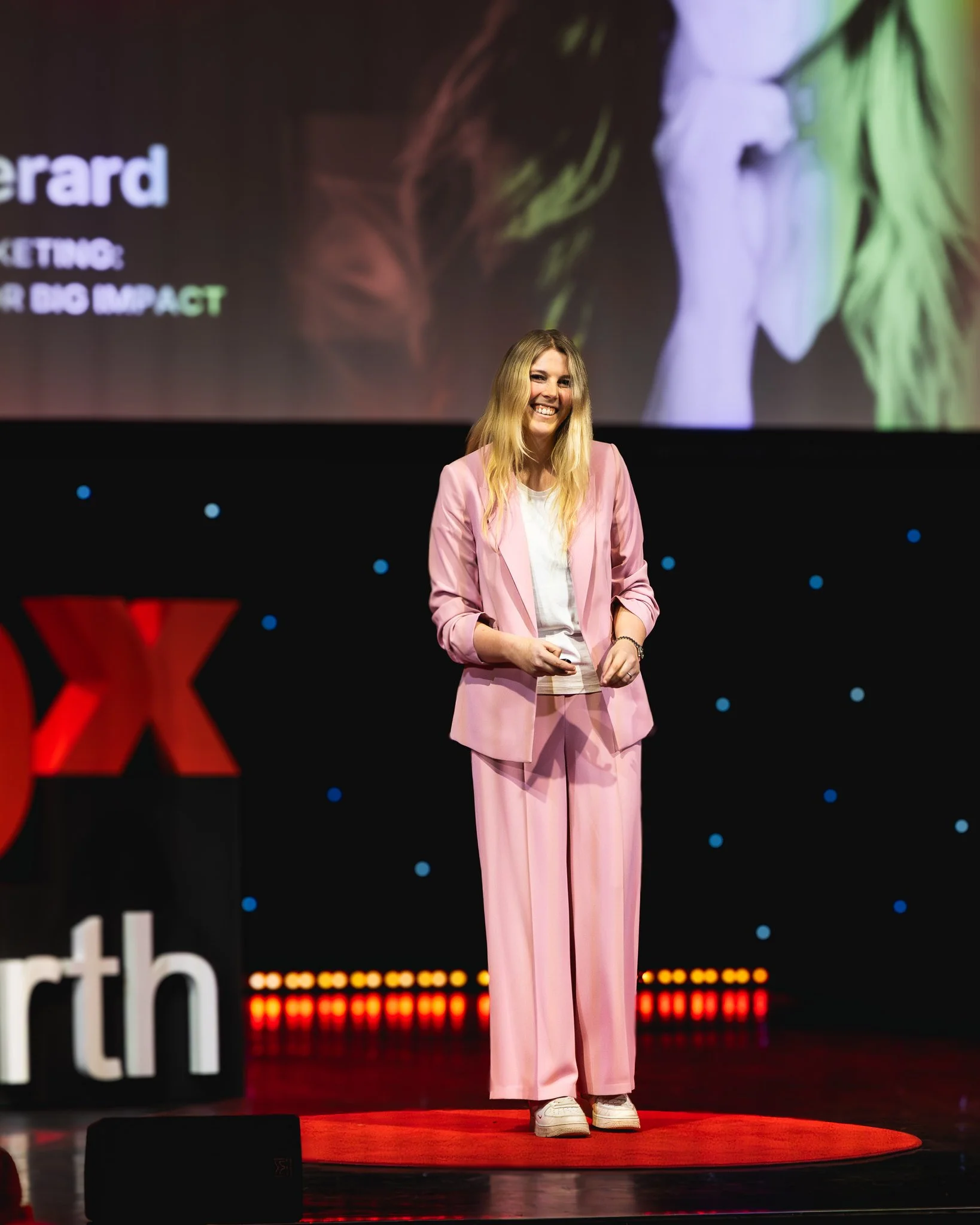 blonde lady wearing a pink suit on a ted talk stage delivering a ted talk