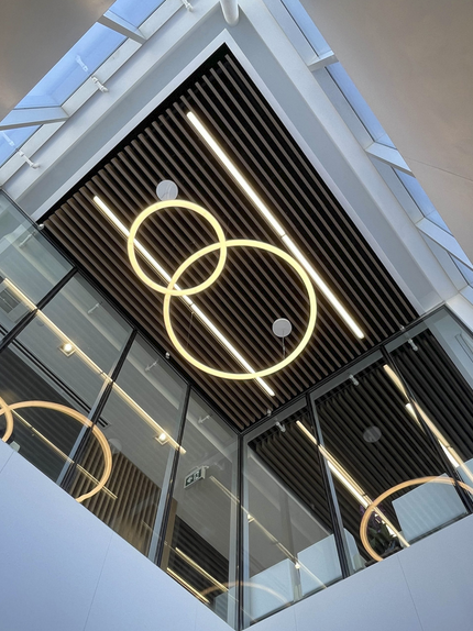 Modern interior ceiling with circular and linear pendant lights and black wooden slat ceiling panels. Healthcare architecture that promotes wellbeing and easier flow and wayfinding. Inspiration for Toronto, Dallas and Park City.
