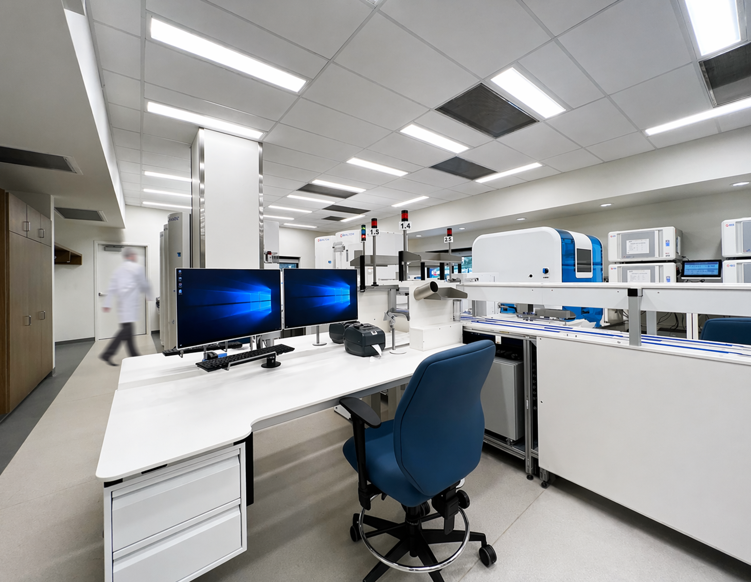 Laboratory with computers, scientific equipment, white desks, and chairs, under a drop ceiling with fluorescent lights. Healthcare architecture that promotes wellbeing and easier wayfinding. Inspiration for Toronto, Dallas and Park City.