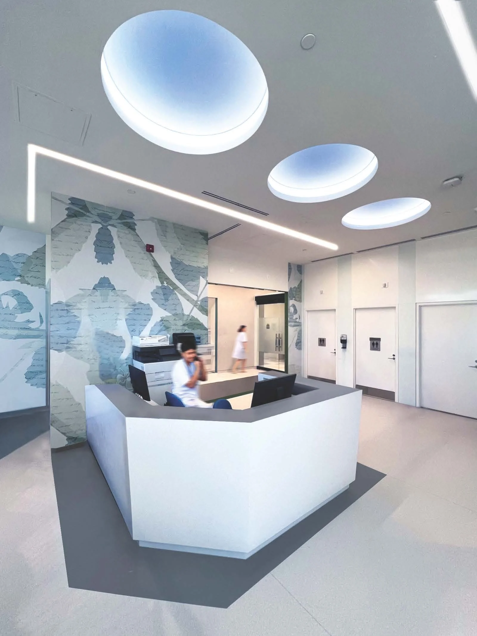 Modern white reception desk in a clinical or office setting with a textured wall featuring a blue floral mural, and two people walking nearby. Salutogenic design, easy flow and wayfinding. Good inspiration for Toronto, Dallas and Park City.