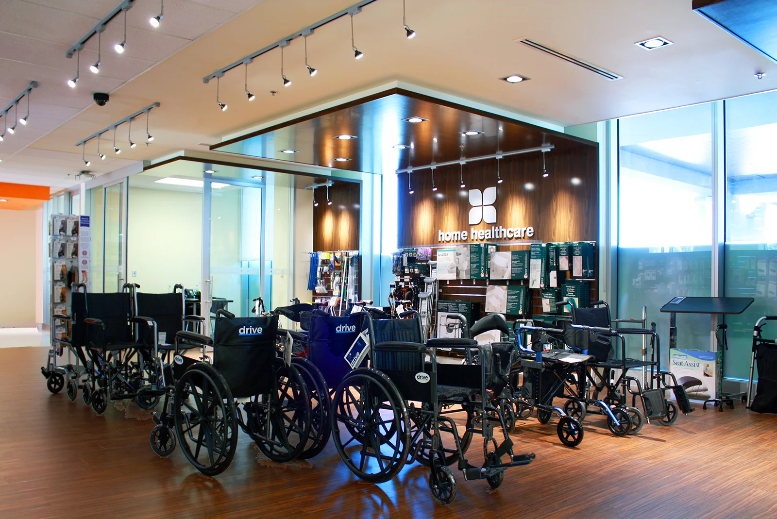 A medical supplies display area in a healthcare facility with several wheelchairs parked in front of a wooden wall with a 'home healthcare' sign, and various medical devices and supplies on shelves.  Toronto, Dallas, Texas, Miami, and Park city.