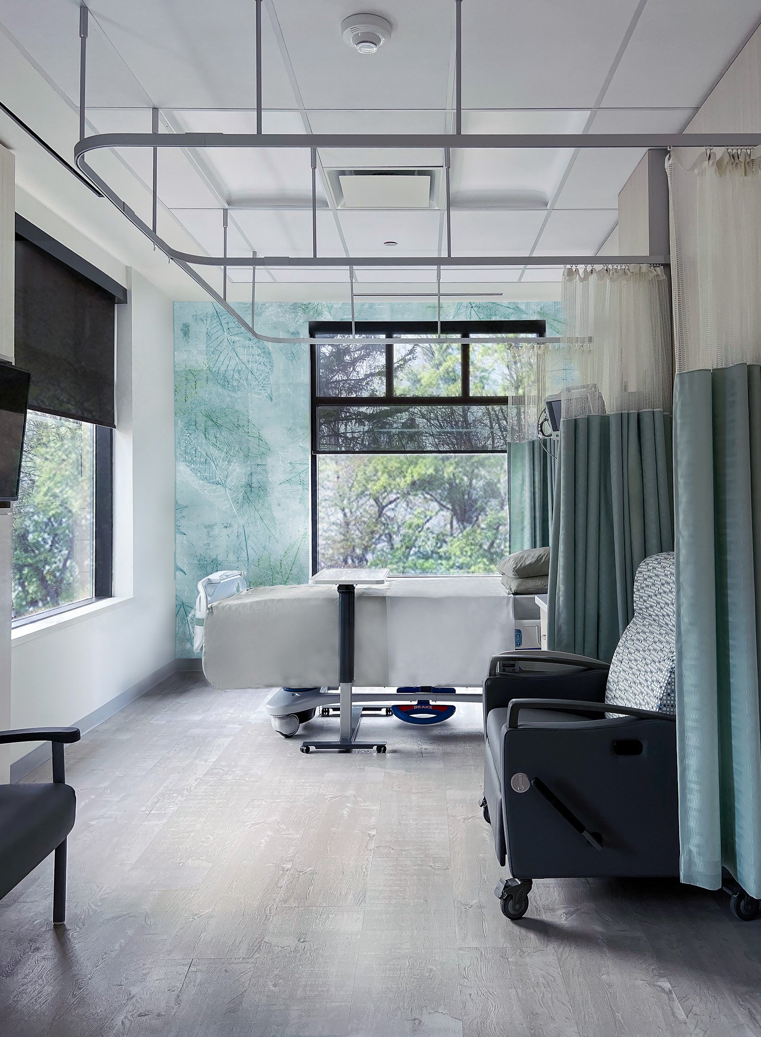 Hospital room with a medical bed, wheelchair, and medical curtains, large windows showing trees outside, and ceiling medical equipment. Good healthcare, salutogenic architecture design inspiration for Toronto, Dallas and Park City.