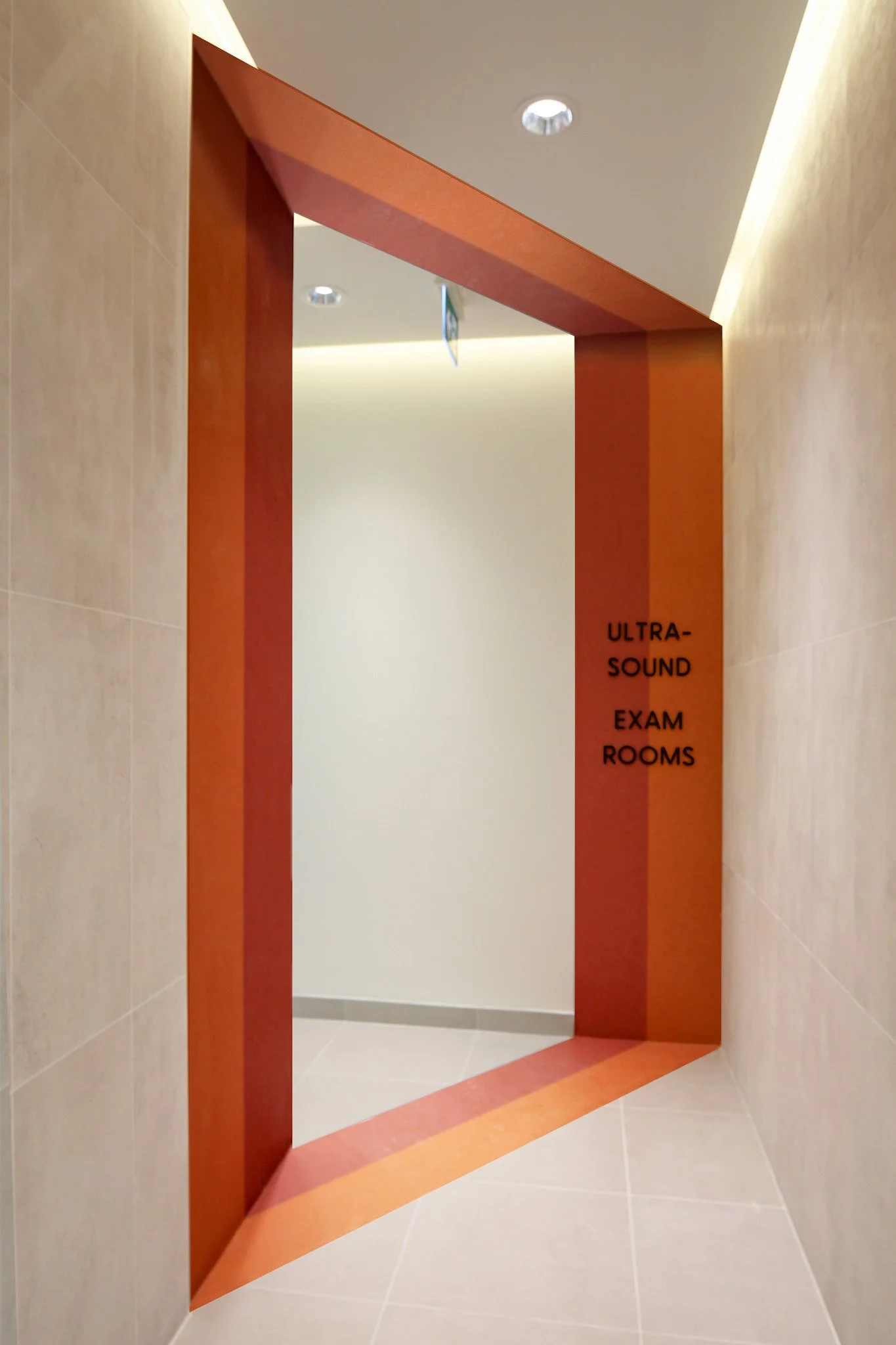 Entrance to ultra-sound exam rooms with a red-orange head-shaped frame and black text on the side. Healthcare architecture that promotes wellbeing and easier wayfinding. Inspiration for Toronto, Dallas and Park City.
