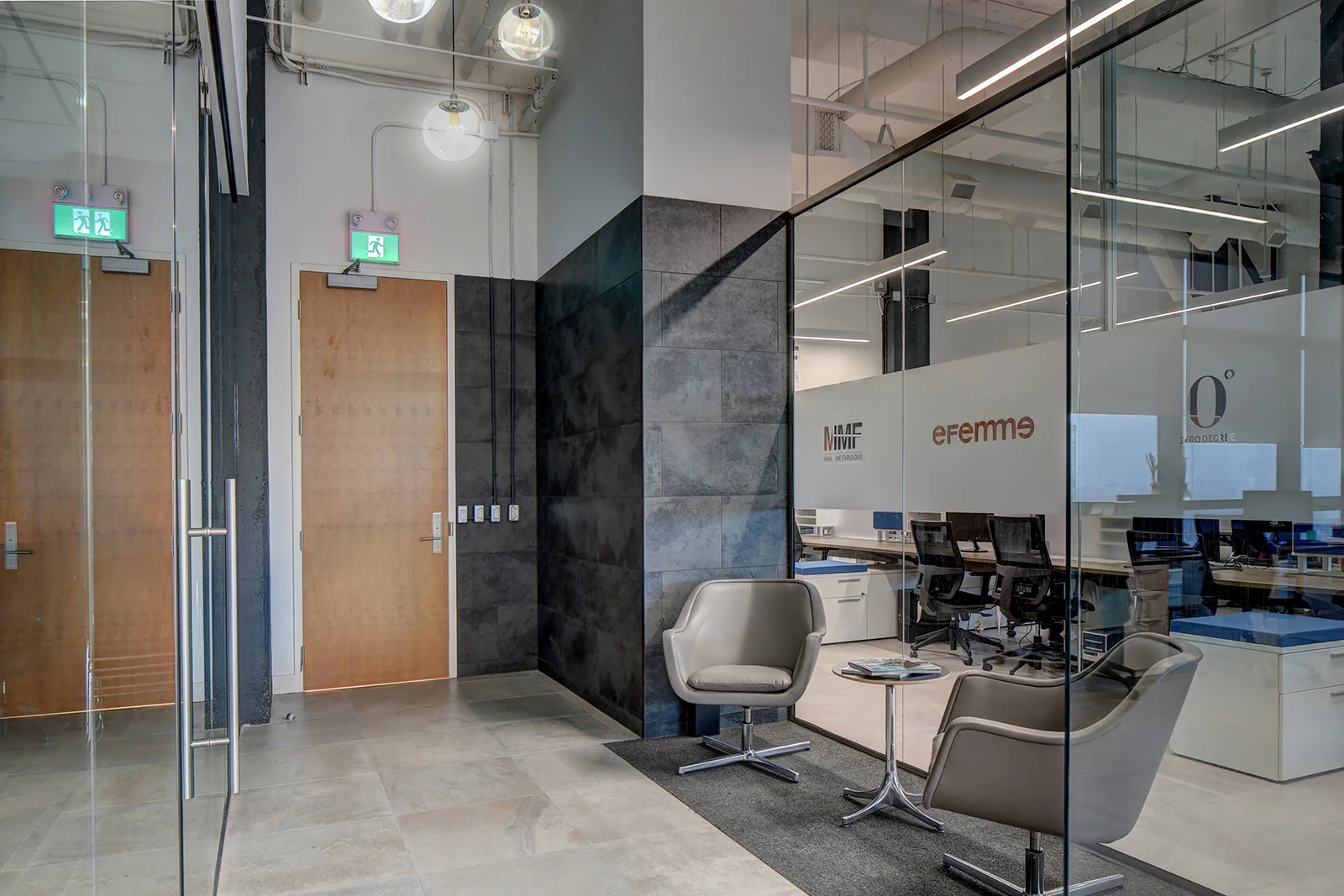 Modern office entrance with glass walls, wooden doors, and a waiting area with two beige chairs and a round table with magazines. Visible conference rooms feature labels such as 'MMF' and 'efemme'. Toronto, Dallas, Park city, Texas, Miami.