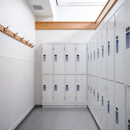 School hallway with white lockers on the right side and a wooden coat rack with hooks on the left wall.