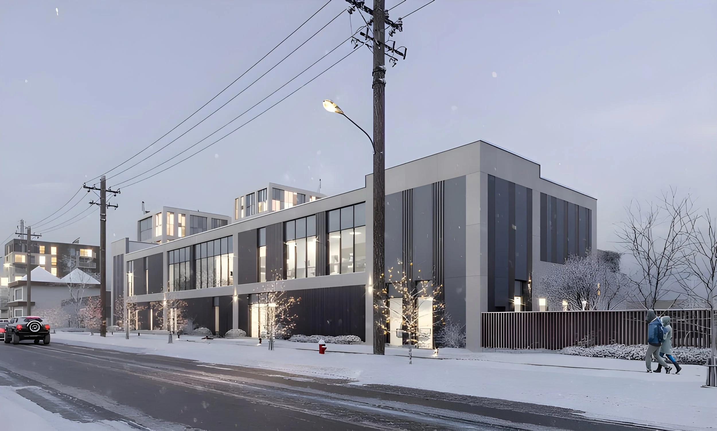 Modern multi-story building with large windows in an urban street scene during winter, with snow on the ground, trees, utility poles, and people walking on the sidewalk.