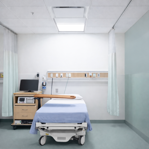 Empty hospital room with a hospital bed, medical monitor, and medical equipment
