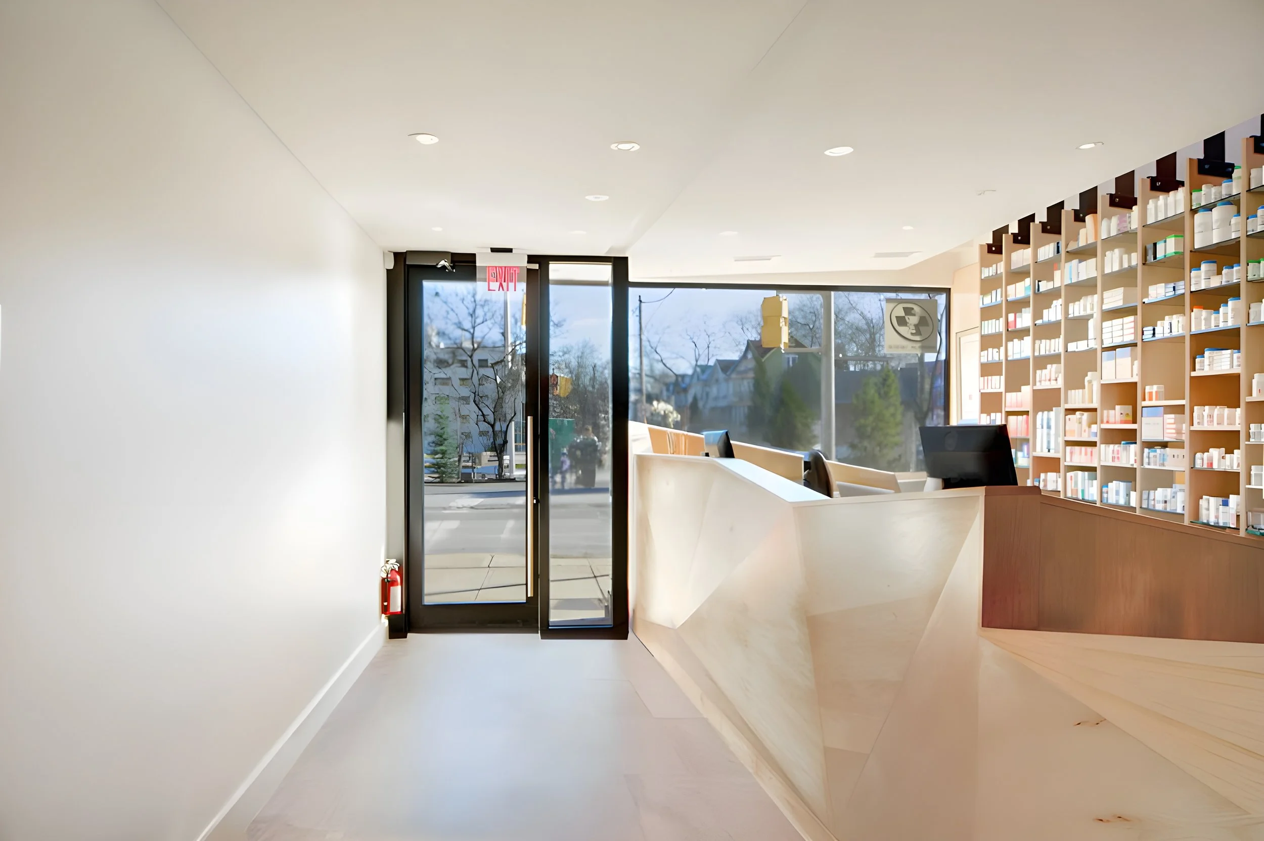 Interior of a modern book store or library with white walls, wood shelves full of books, and large windows letting in natural light.