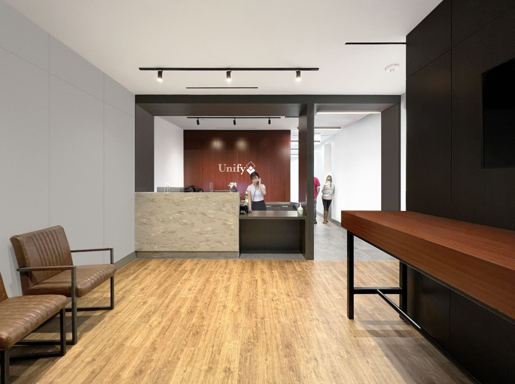 Reception area in a modern healthcare lobby in Toronto, with a wooden floor and gray and black walls and a red accent wall. Inspiration for Miami, Park City, Dallas and Texas. Salutogenic design, human flow, beautiful architecture, human design.