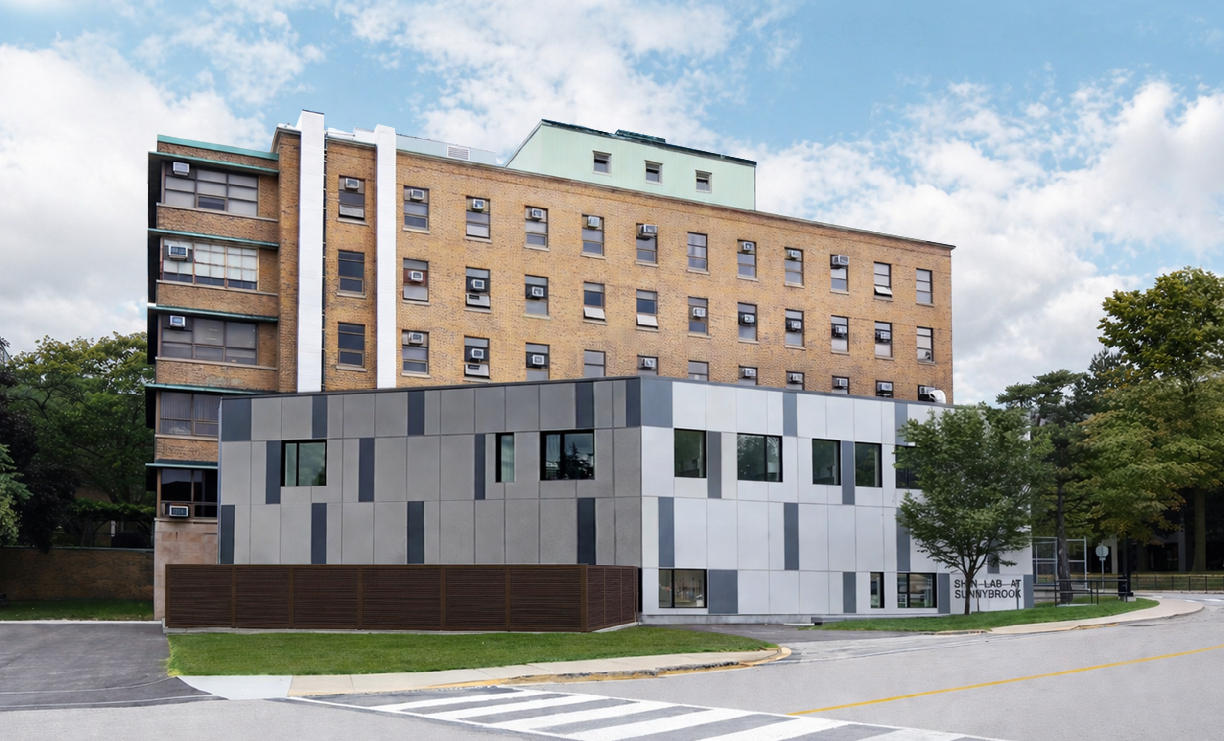  Modern multi-story building with brick and facade panels, surrounded by trees and a street with a crosswalk in the foreground. Healthcare architecture that promotes wellbeing and easier wayfinding. Inspiration for Toronto, Dallas and Park City.