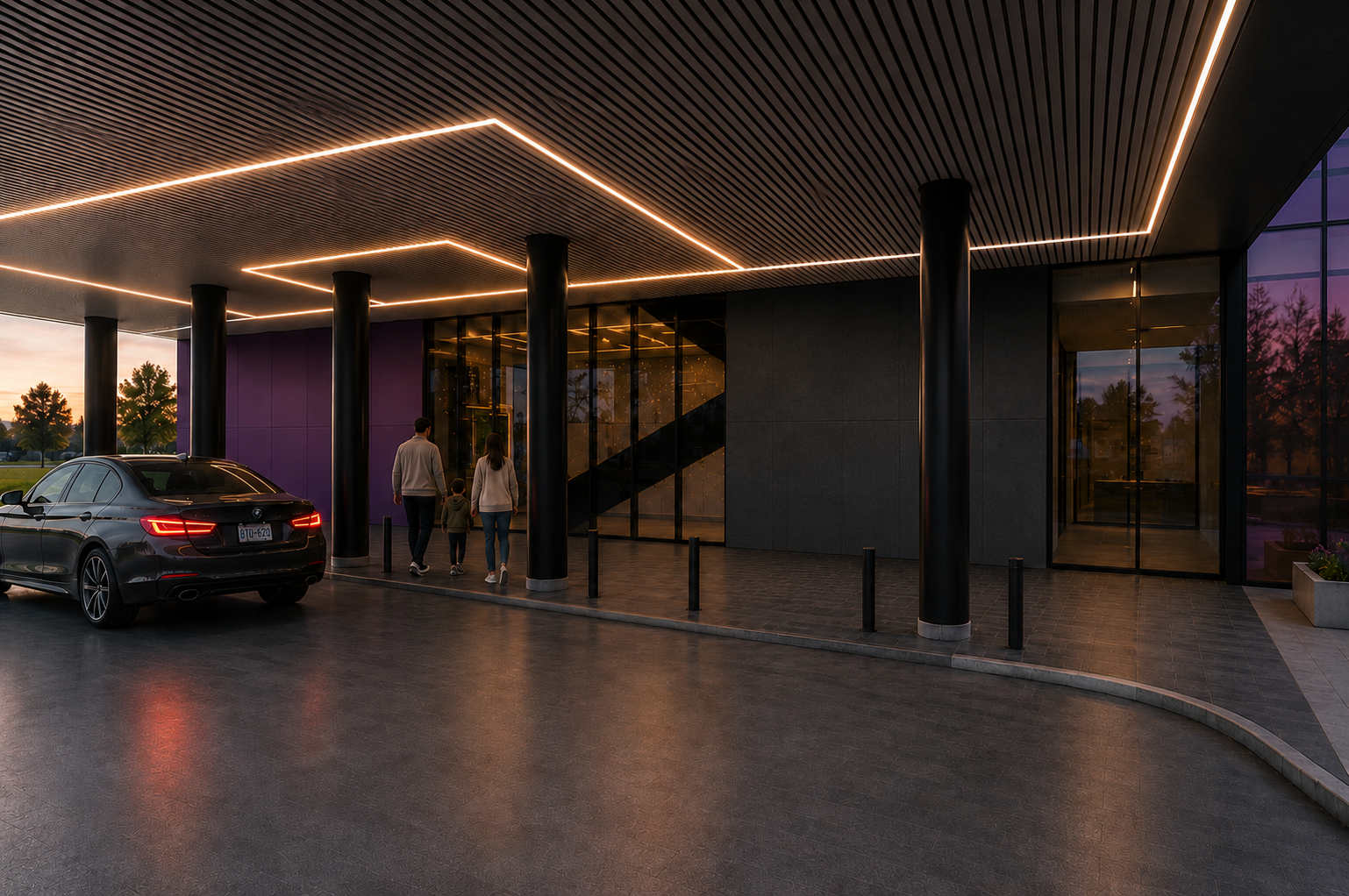 People walking into a modern building entrance with a car parked nearby, illuminated by warm lighting at sunset.