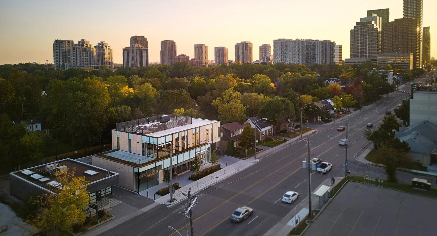 A cityscape with a mix of modern high-rise buildings and a leafy residential area in Toronto, ON, featuring a contemporary commercial building in the foreground.  Focus on healthcare, specialized healthcare. Good inspiration for Dallas and Park City.
