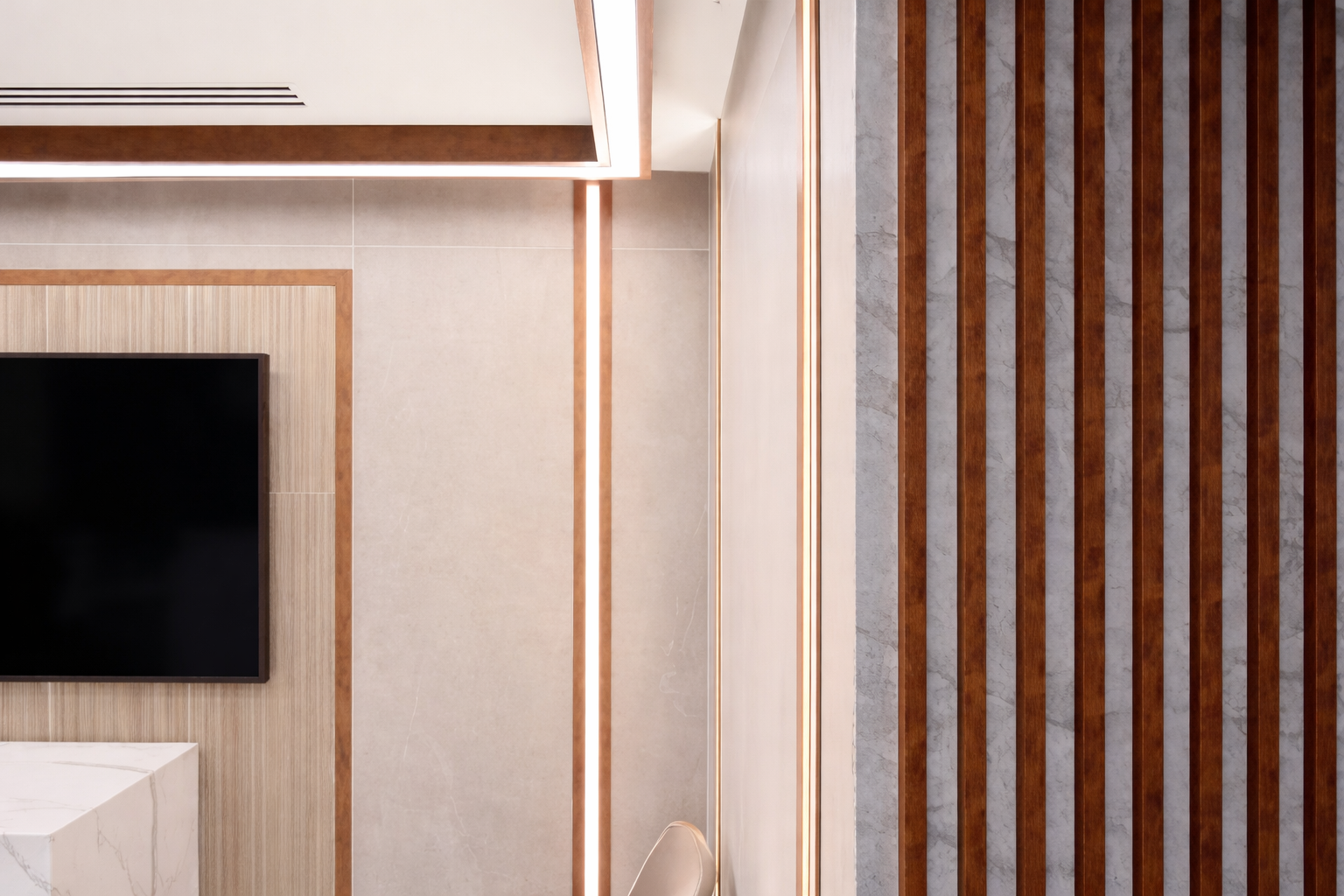 Interior view of a modern room with a mounted flat-screen television, a light-colored wall with wooden trim, and a decorative wall panel with vertical wooden slats.