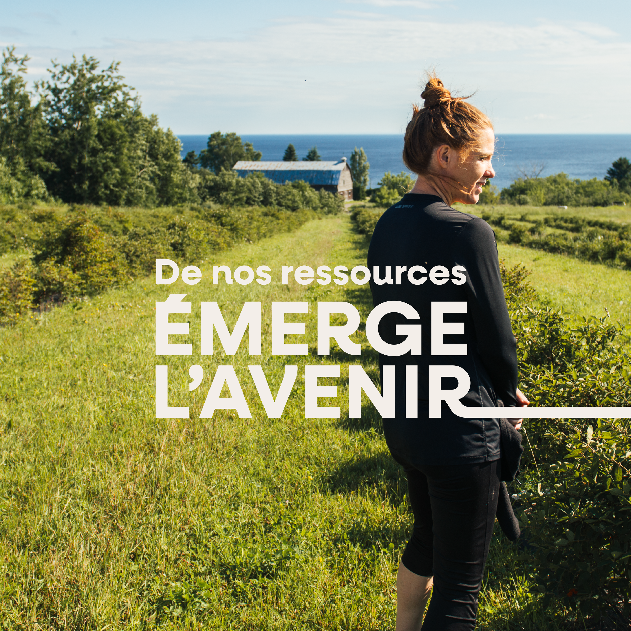 Une femme souriante dans un champ vert, avec la mer en arrière-plan, entourée d'arbres, en train de cueillir des fruits ou des légumes.