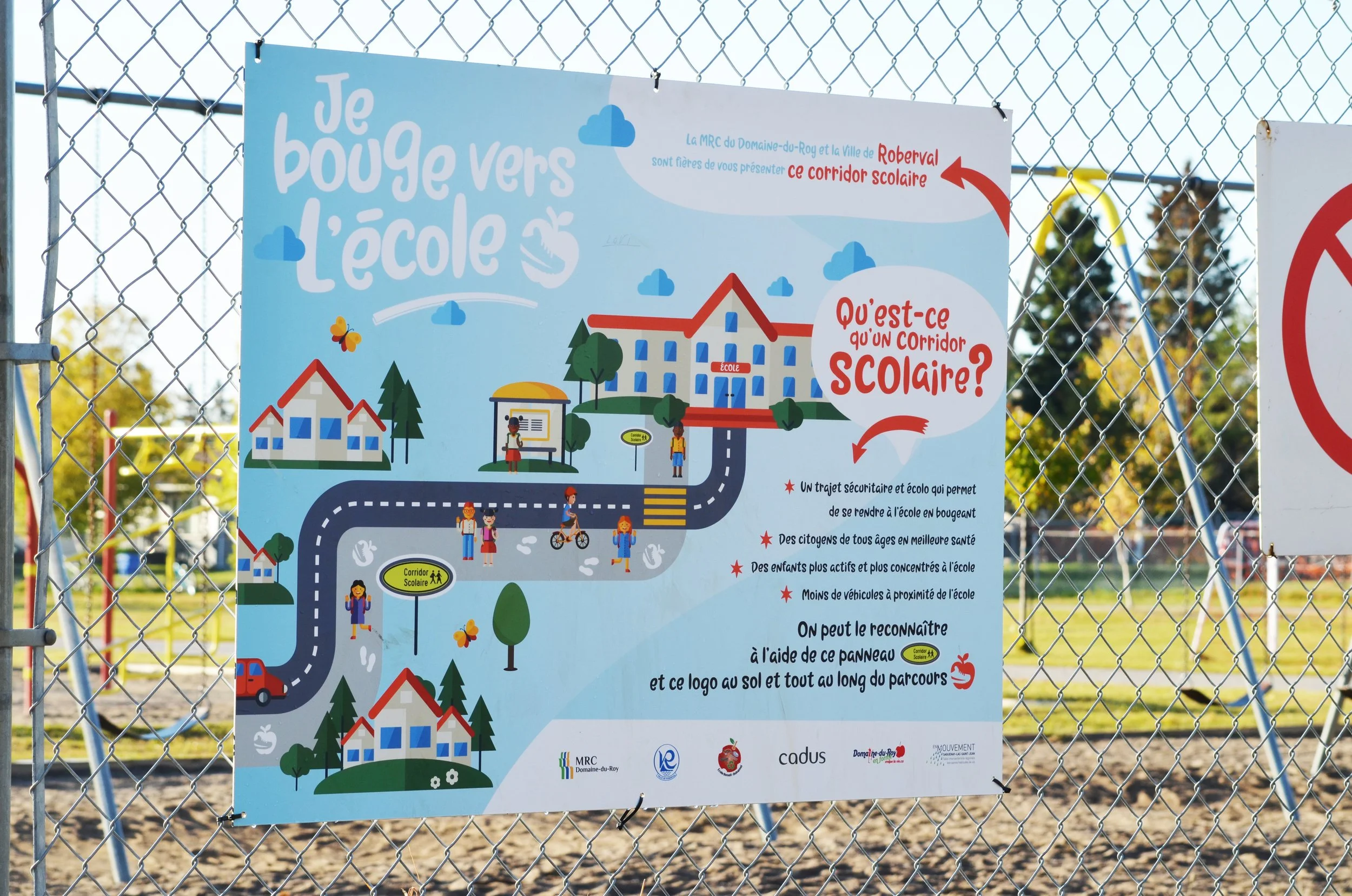 Panneau d'information sur le corridor scolaire à proximité d'une école, illustrant un chemin sécurisé pour les enfants, avec des dessins d'élèves, de véhicules, d'arbres, et des éléments de signalisation.