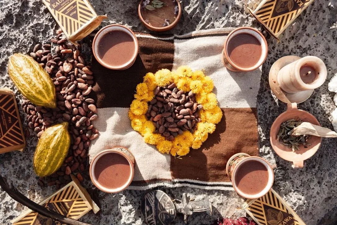 Infusion de cacao cérémonielle dans 4 tasses, avec des fleurs et des fèves de cacao disposées au centre d'un tissu