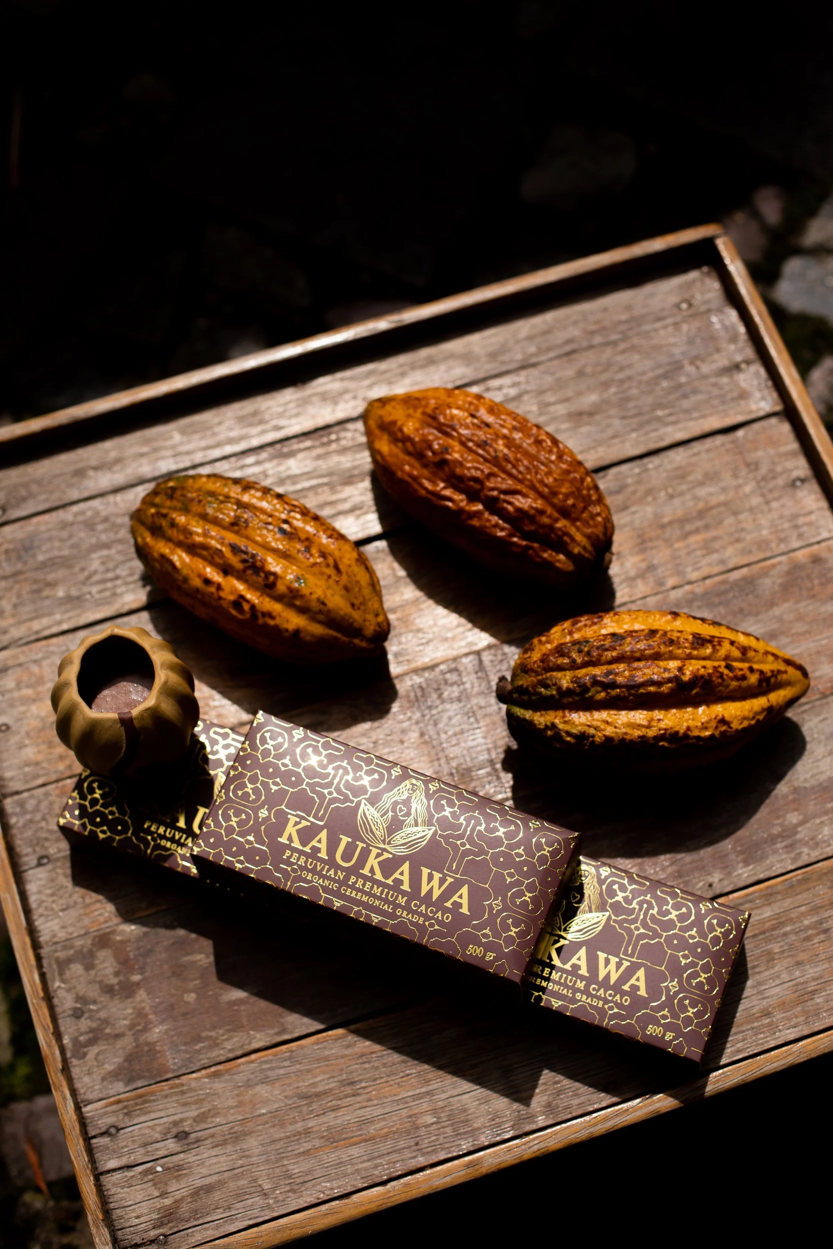 Kaukawa bars laid on a wooden board with Cacao fruit and a brew