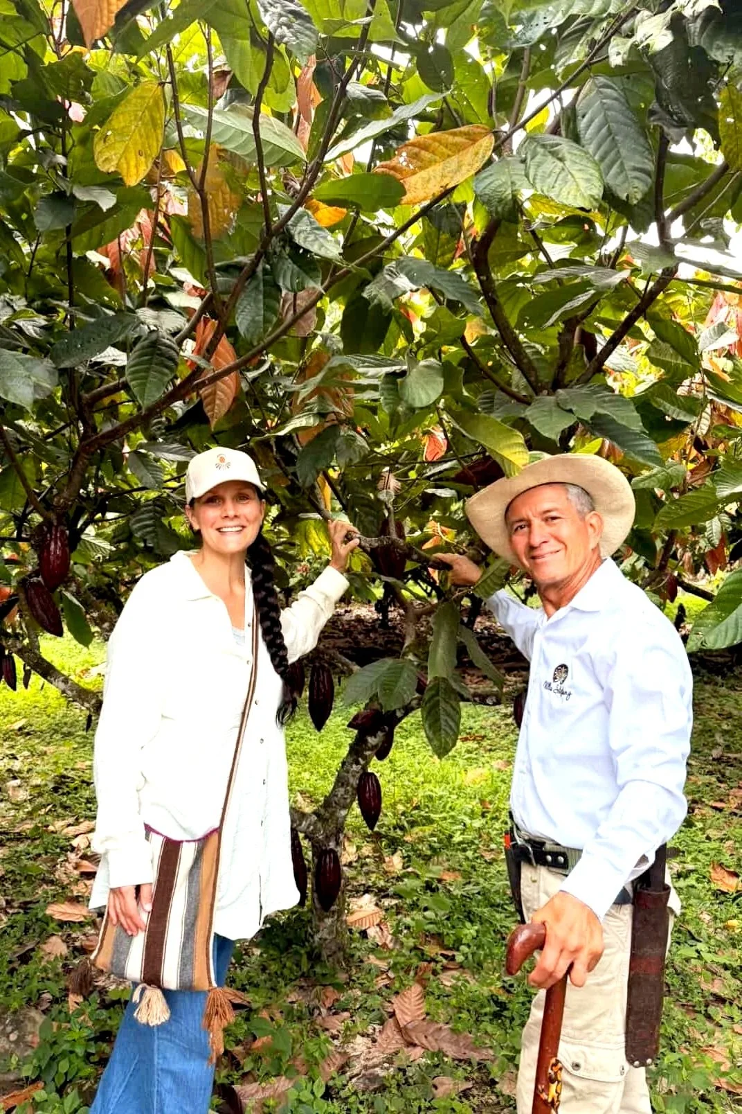 Nicole, la fondatrice, et Señor Bernardo de Caonia sourient devant un cacaoyer.