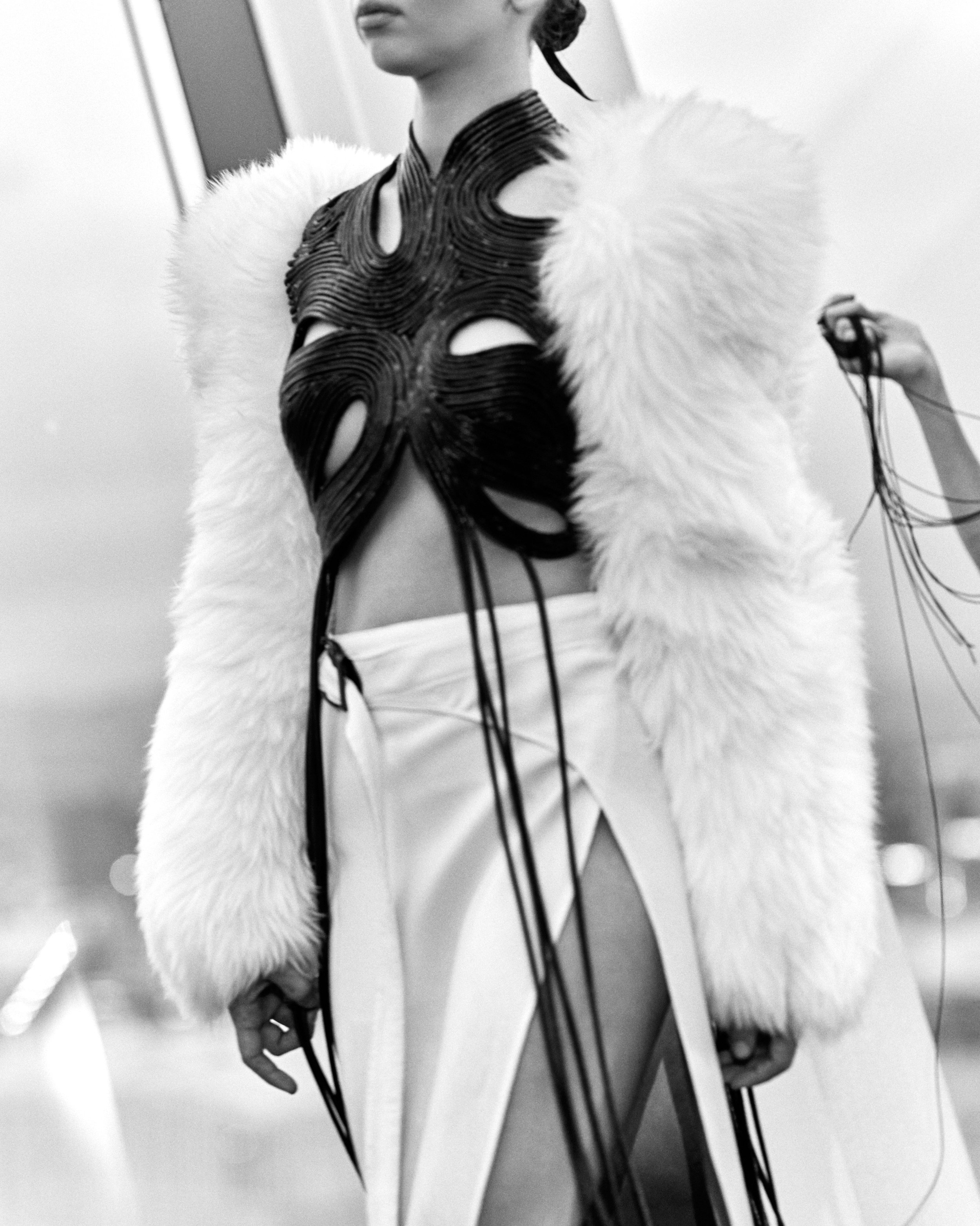 Fashion model in avant-garde outfit with fur sleeves and cut-out top