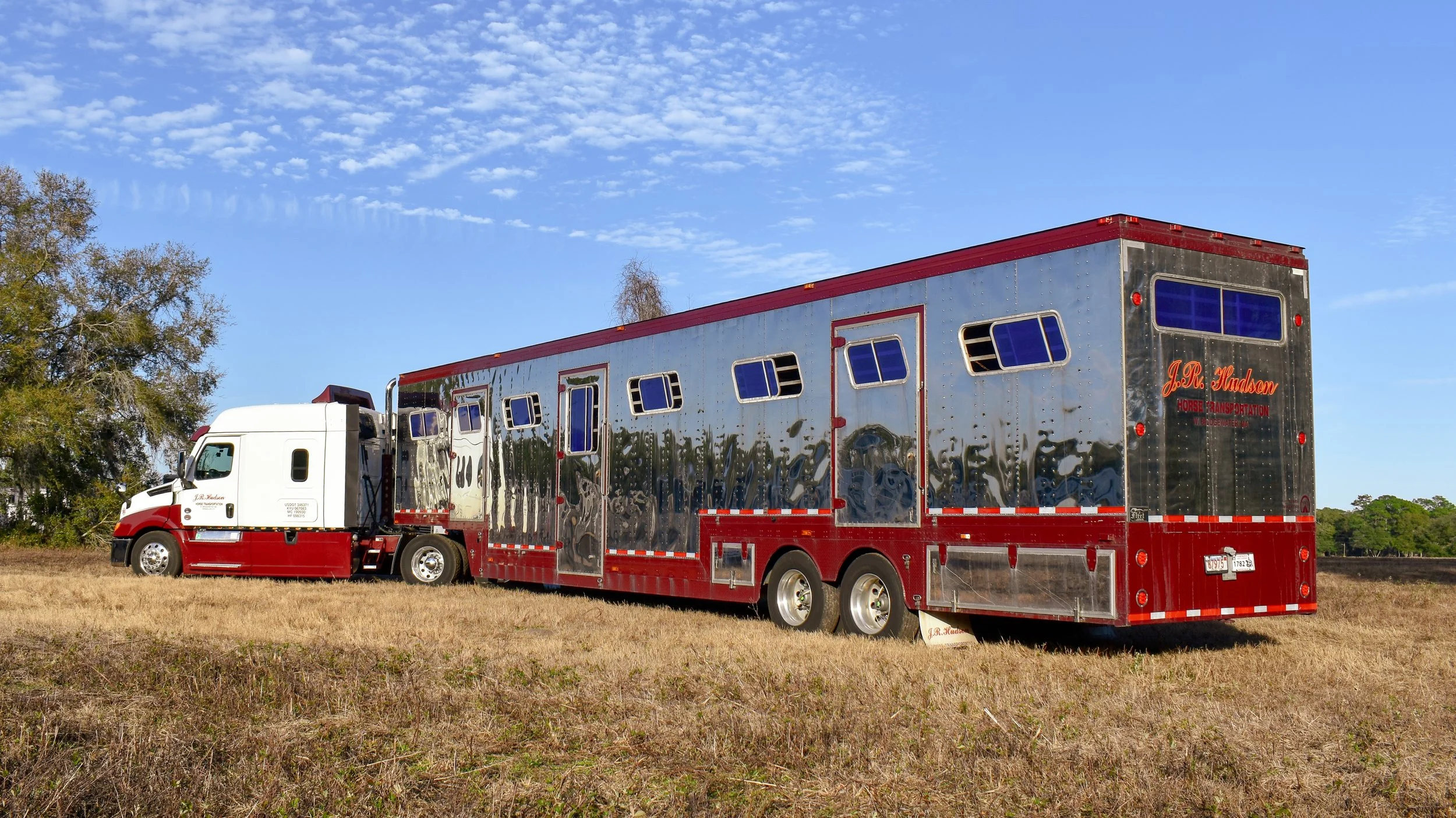 J.R. Hudson Horse Transportation truck with a stainless steel trailer and a white cab, parked at the World Equestrian Center in Ocala, Florida