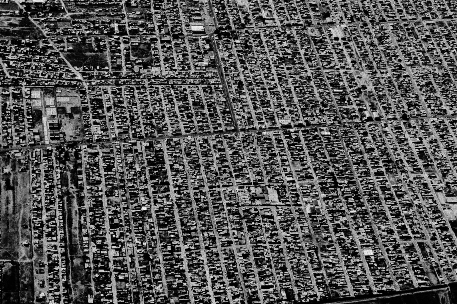 Aerial view of a densely packed residential area with numerous small, closely spaced row houses and narrow streets.