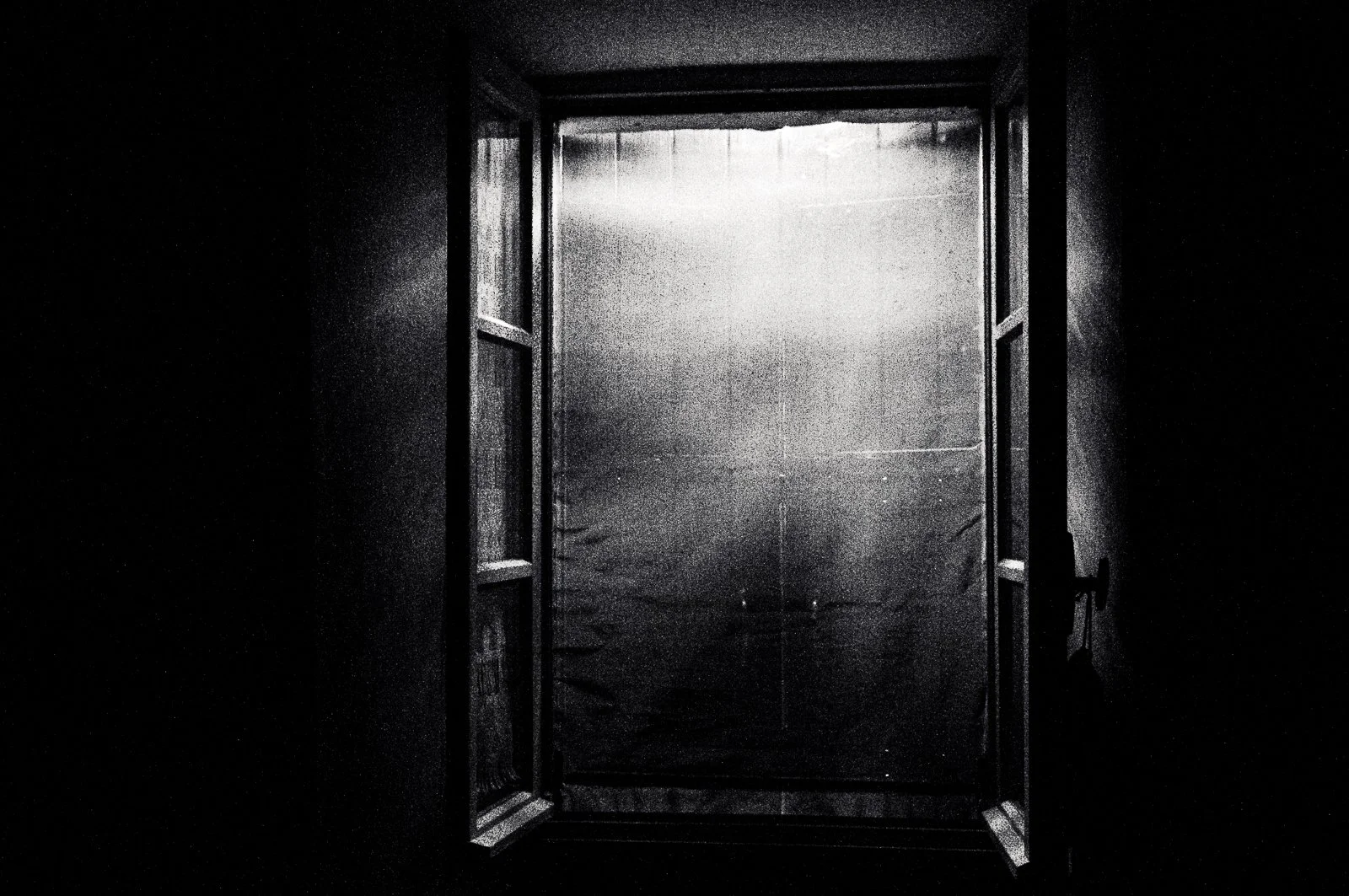 Open door to a foggy or misty outdoor scene with a bright light shining through the doorway, creating a silhouette effect.
