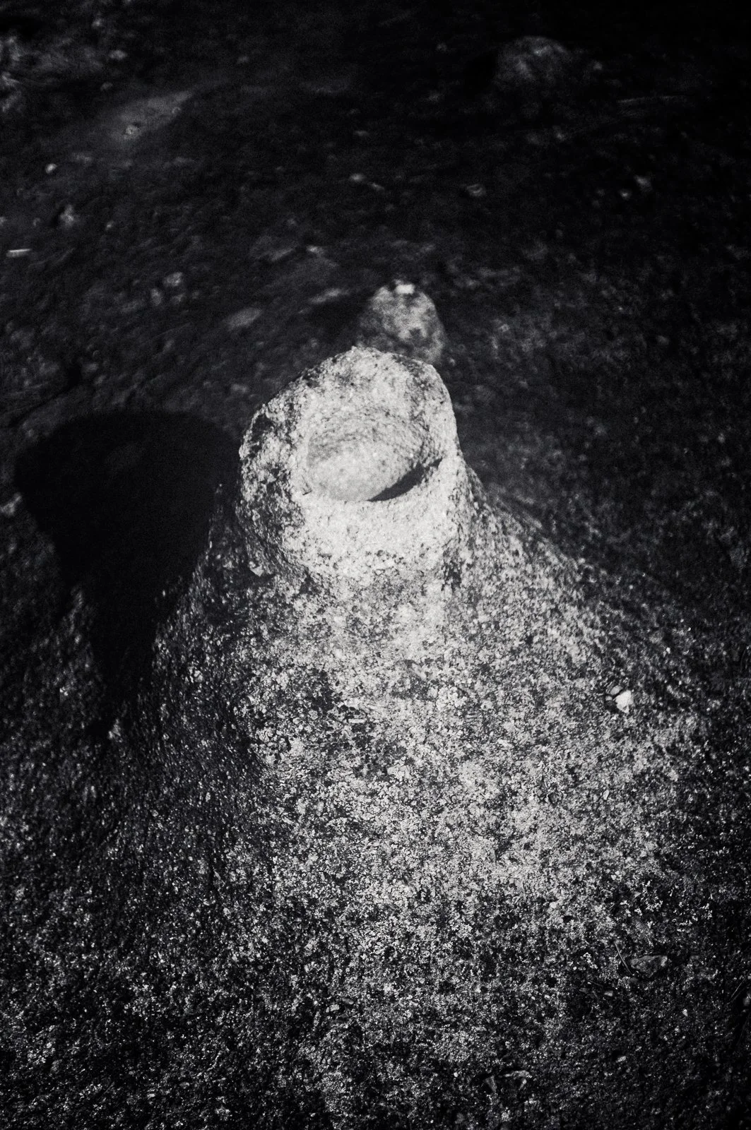 Sandcastle on dark sandy surface, with a small sand tunnel in the middle