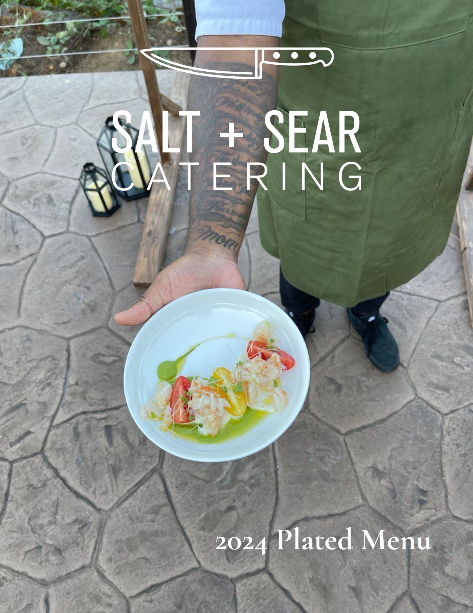 Chef holding a white plate with artisanal food, showcasing tomatoes and garnished elements. Text reads: 'Salt + Sear Catering, 2024 Plated Menu.' Chef wearing a green apron and has visible tattoos.