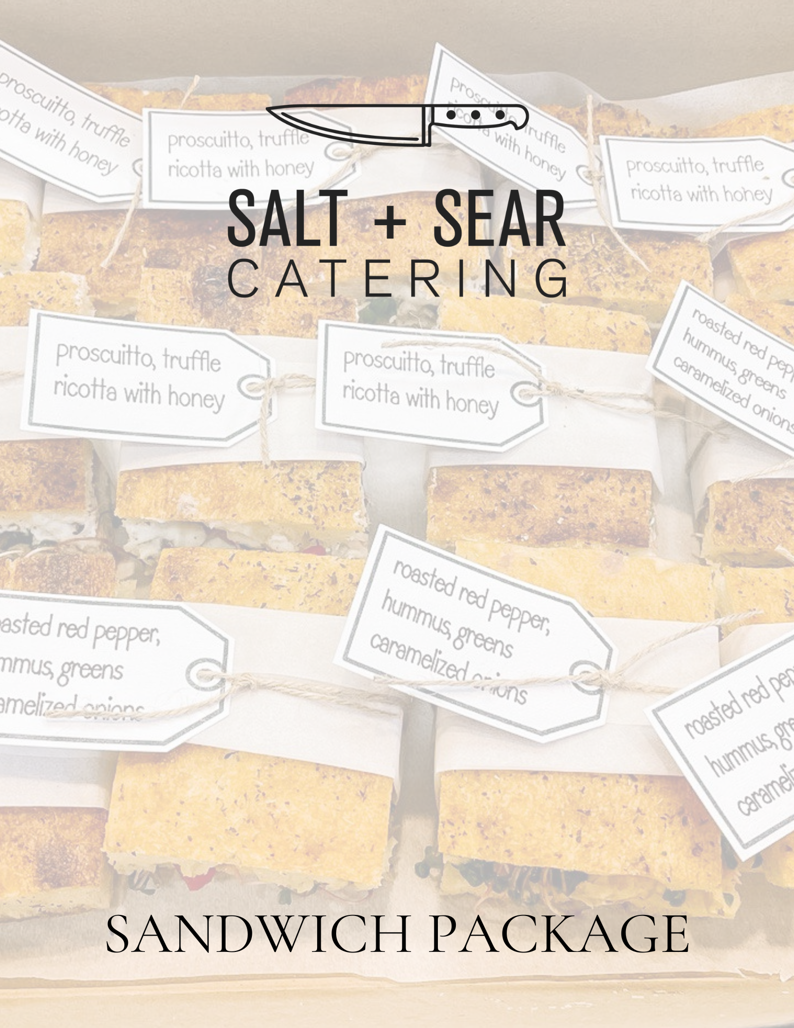 Assorted gourmet sandwiches arranged in a box with tags, labeled "Salt + Sear Catering" and "Sandwich Package."