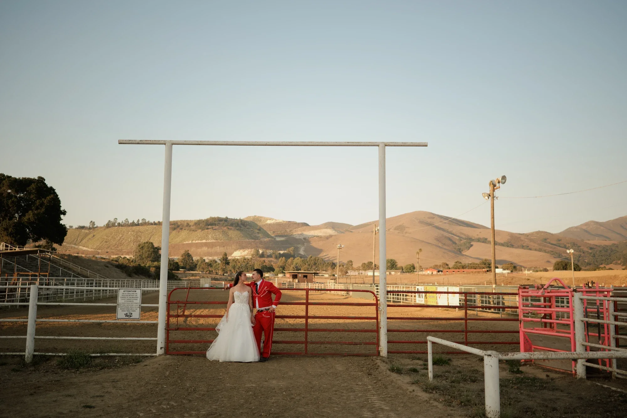 Danielle and Rhett posing by a farm pen during golden hour with Partial Planning Services