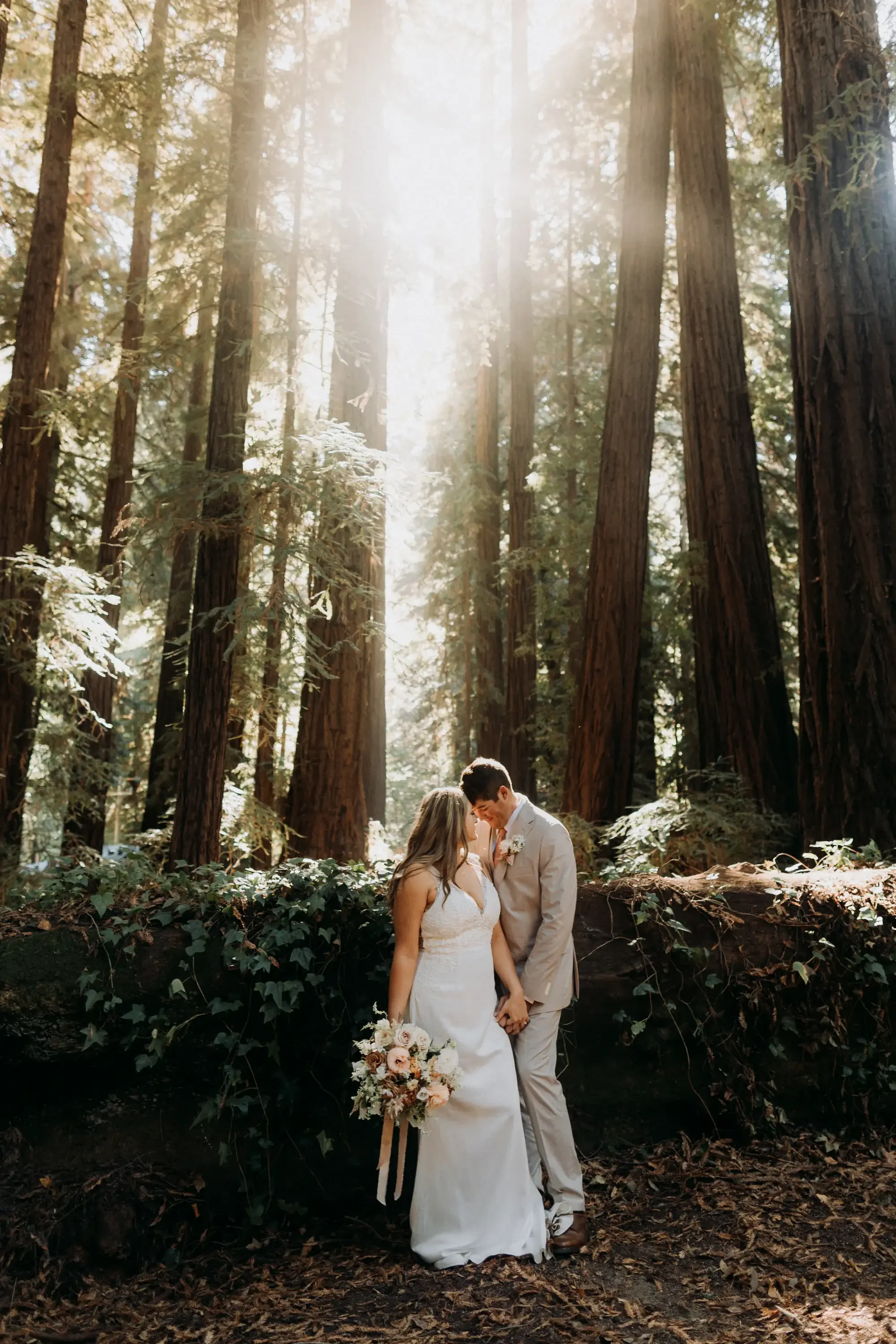 April and Trey sharing an embrace in the forest during their Big Sur elopement