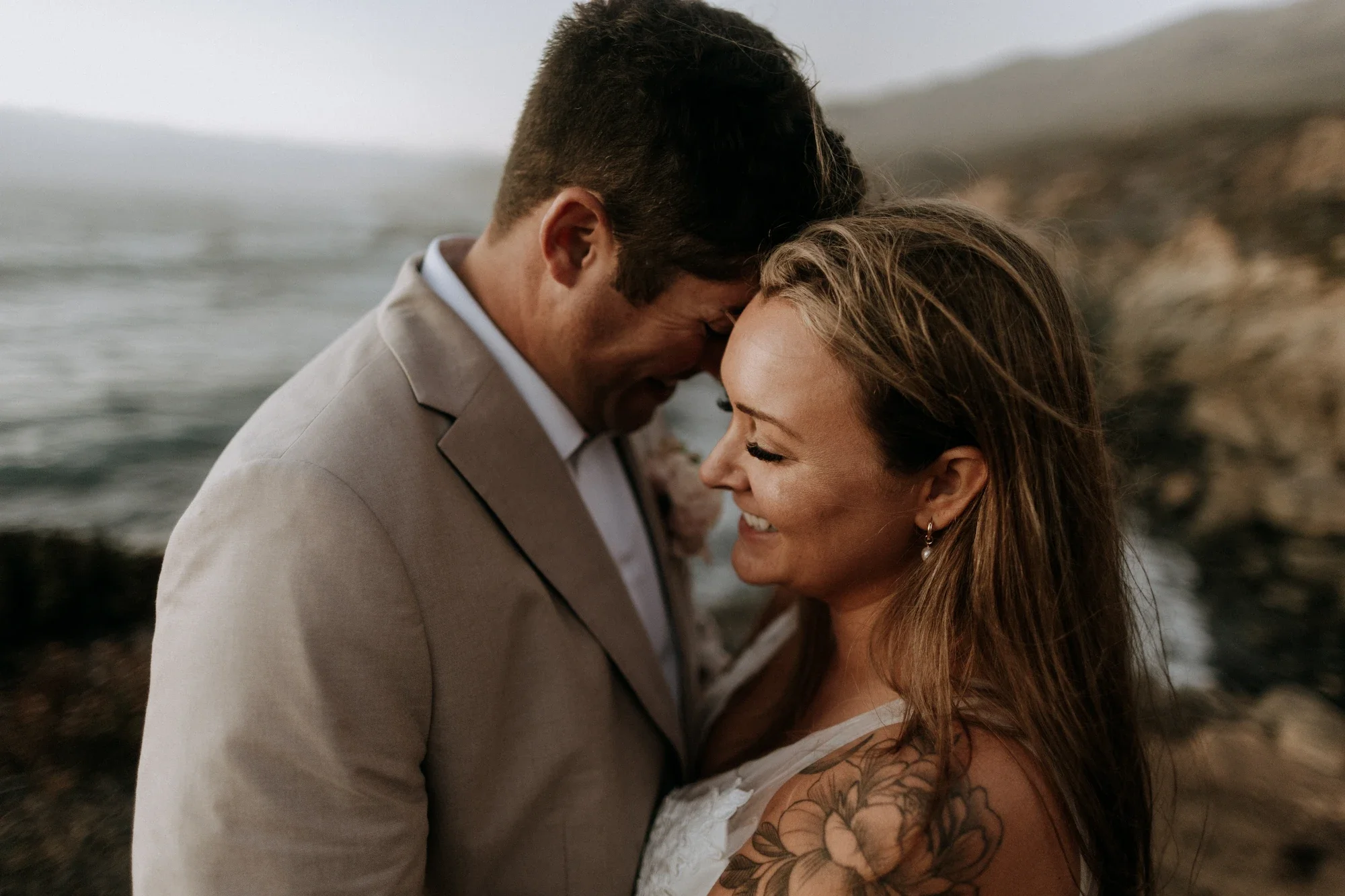 April and Trey smiling over the cliffs during their Big Sur elopement