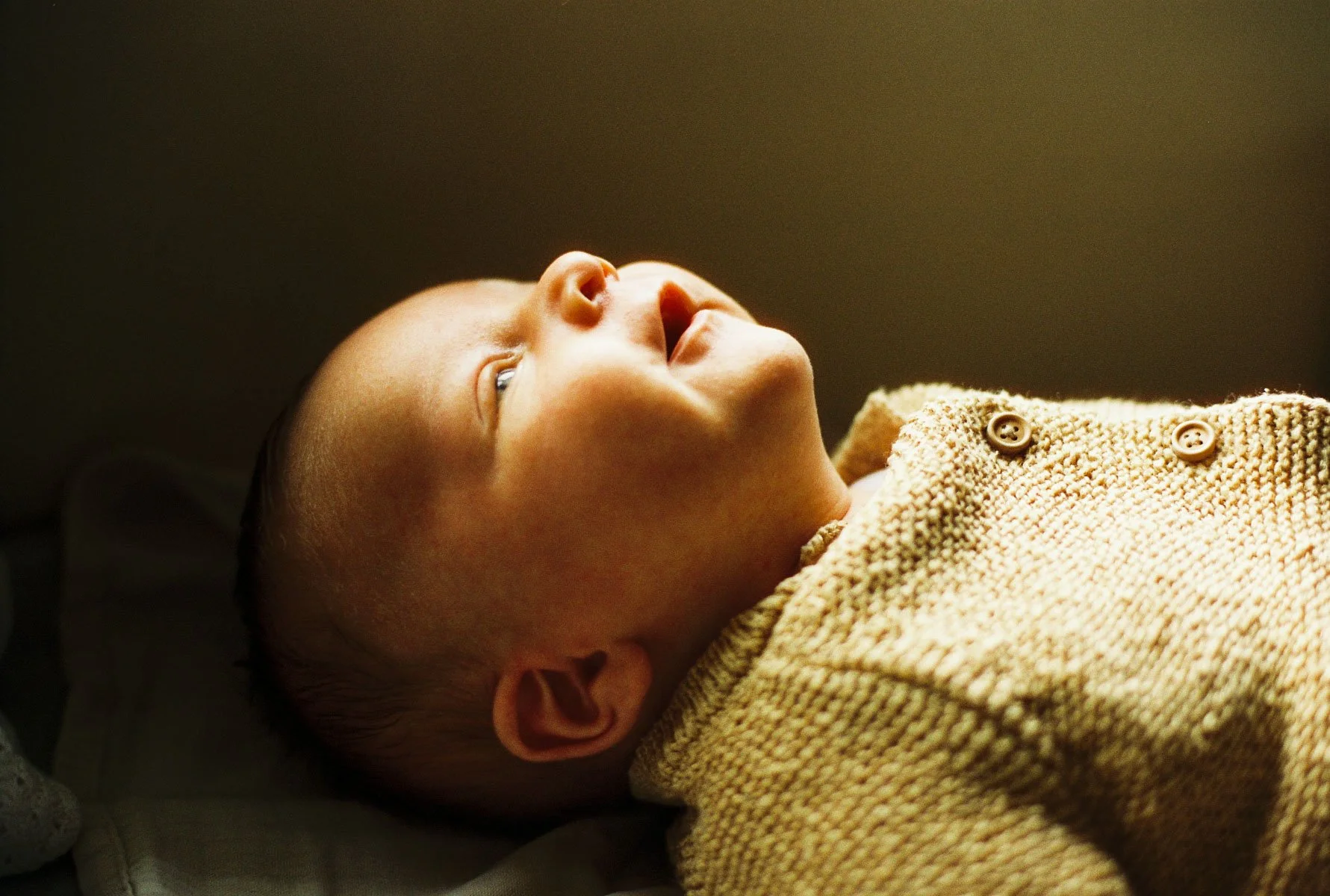 Newborn baby wearing mustard yellow knitwear during a Dublin in-home 35mm film session.