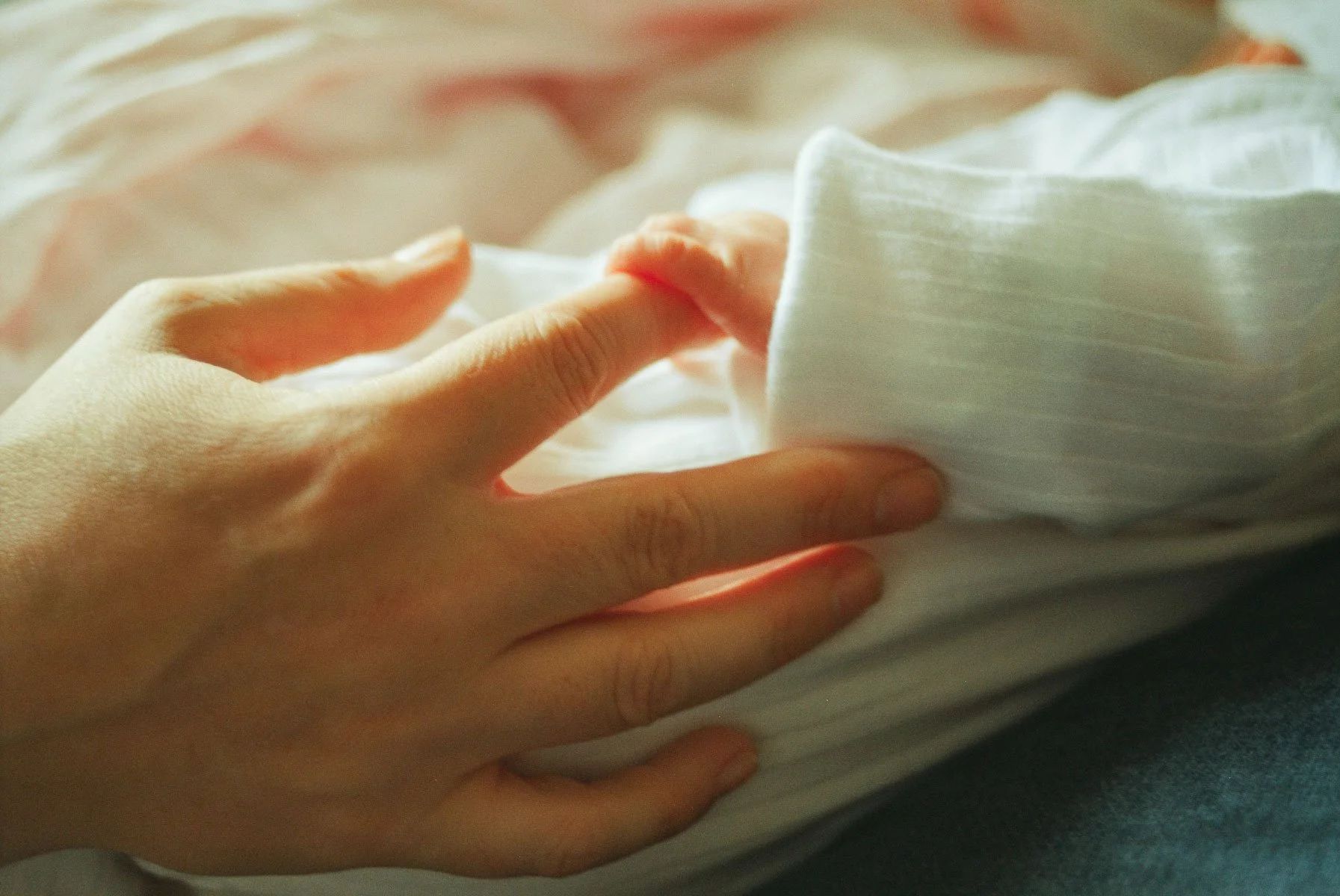 Detail shot of a newborn baby's hand against white fabric, shot on 35mm film by a Dublin newborn photographer.