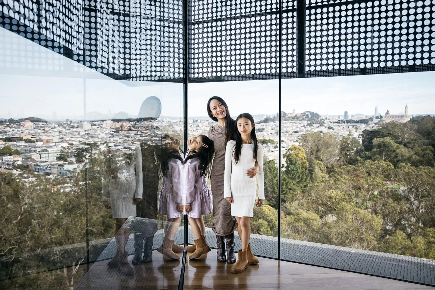 Single mom and two daughters stand hugging in the tower at the deYoung Museum in San Francisco. From single parent family photo session.