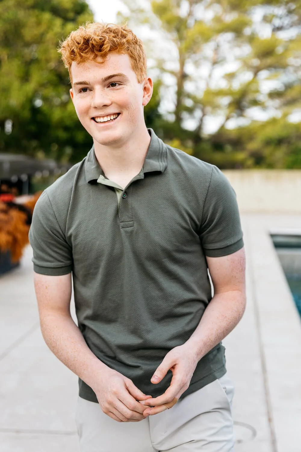 Senior portrait of redheaded boy in backyard with pool and oak trees, shot in Orinda, CA.