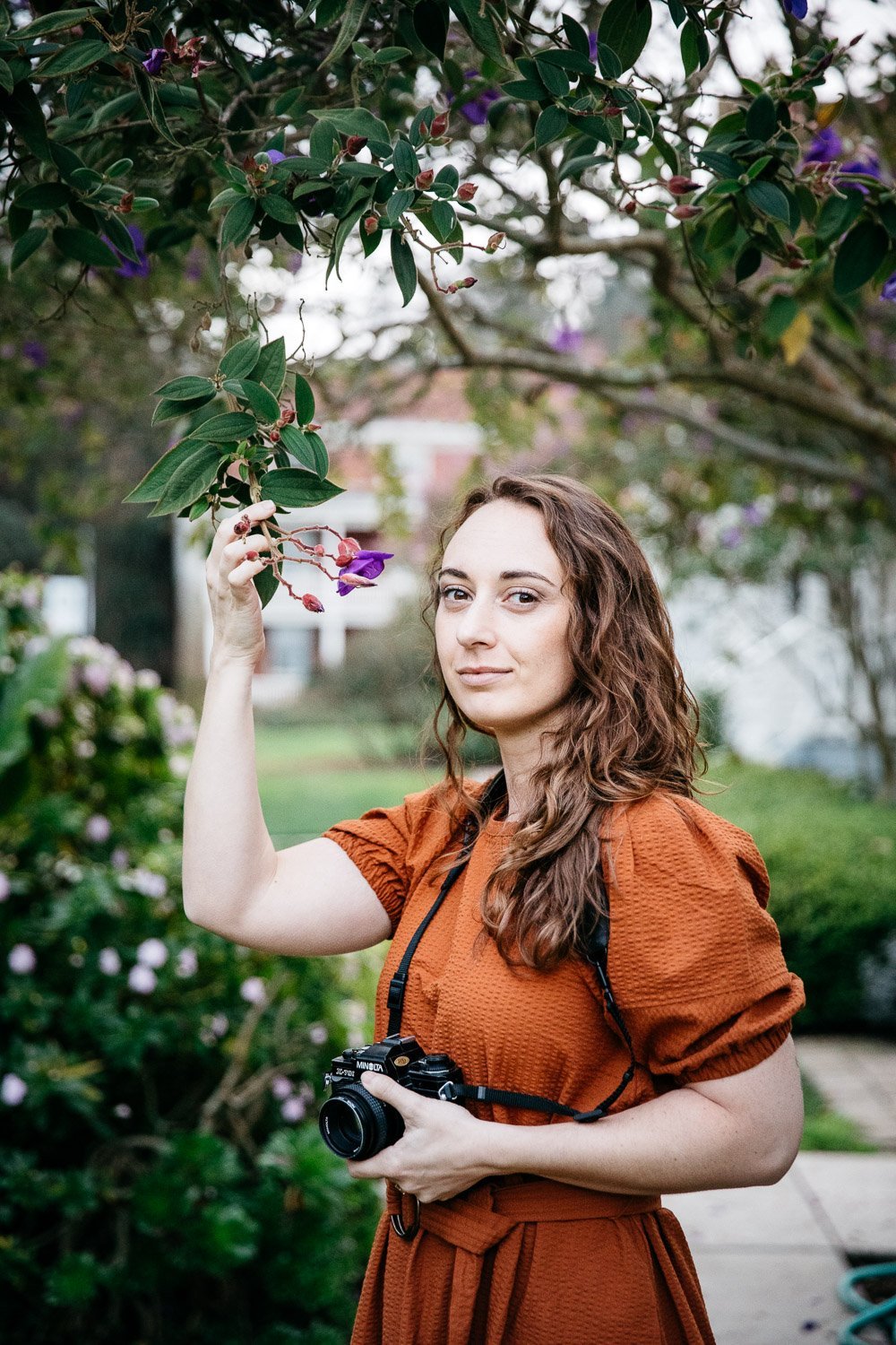  brand portrait of photographer Toni Toscano looking at camera and shot through tree with purple flowers, shot in the Presidio in San Francisco by brand photographer Allison Busch Photography 