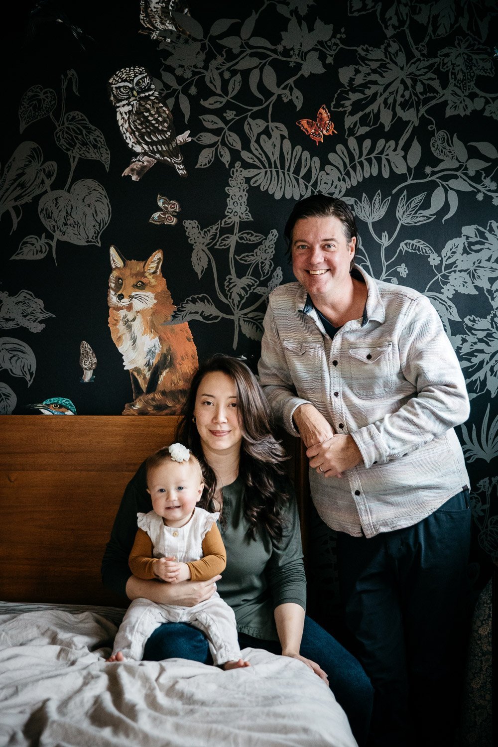  family photograph of mom, dad, and baby at home in bed with soft light and fun wallpaper, shot in Berkeley by family photographer Allison Busch Photography 