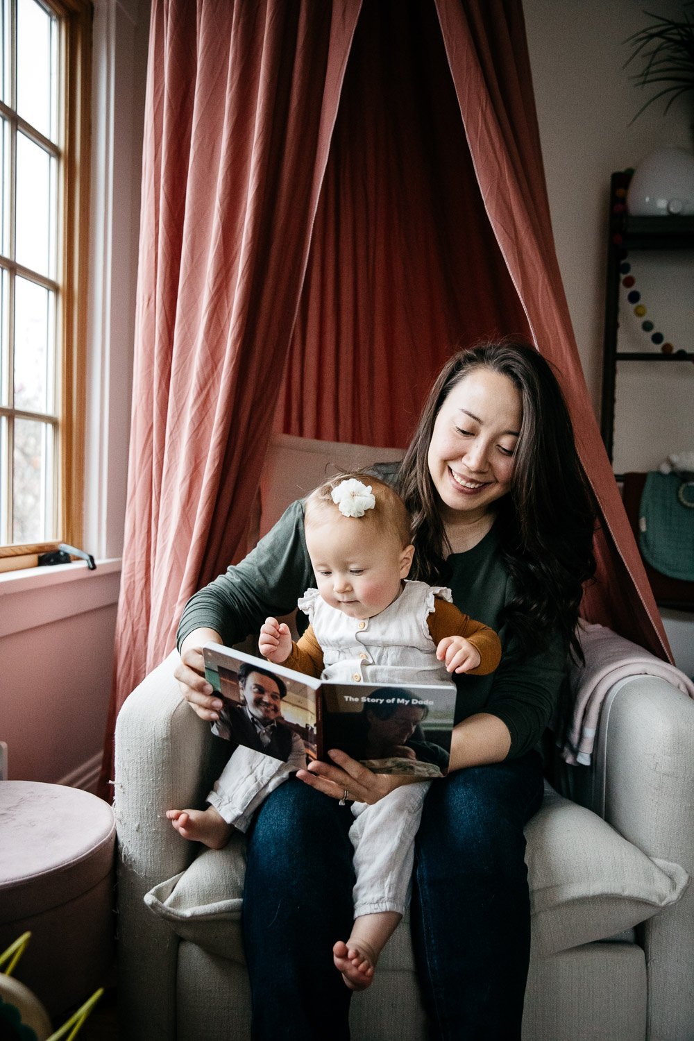  family photograph of mom and baby at home sitting in chair with baby book, shot in Berkeley by family photographer Allison Busch Photography 