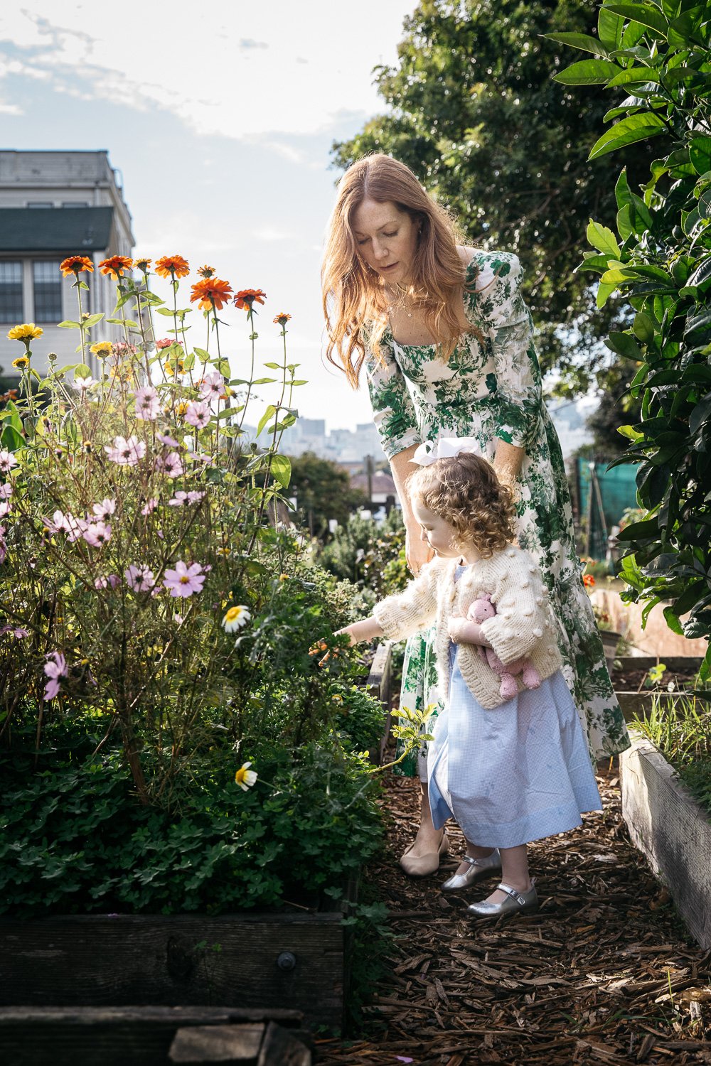 Mom and daughter wear flowered dresses in garden at Fort Mason in San Francisco.